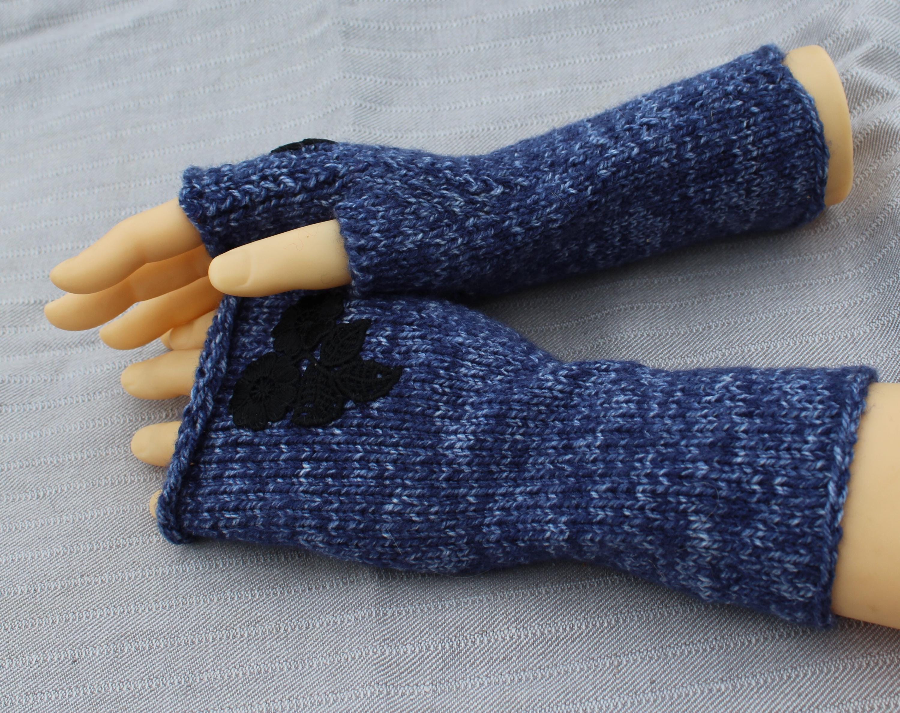 Blue knitted fingerless gloves on a mannequin arm against a gray background