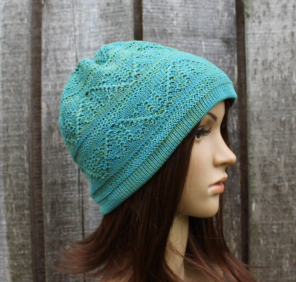 Teal knitted hat on a mannequin head against a wooden background