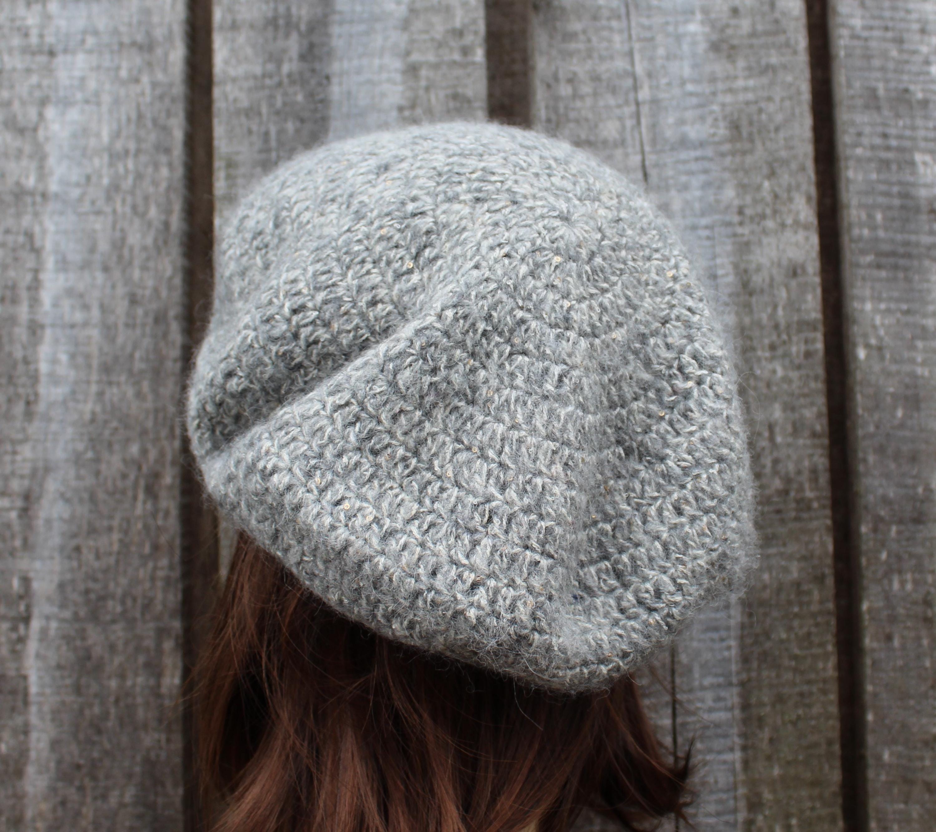 Gray knitted beanie worn by a person against a wooden background