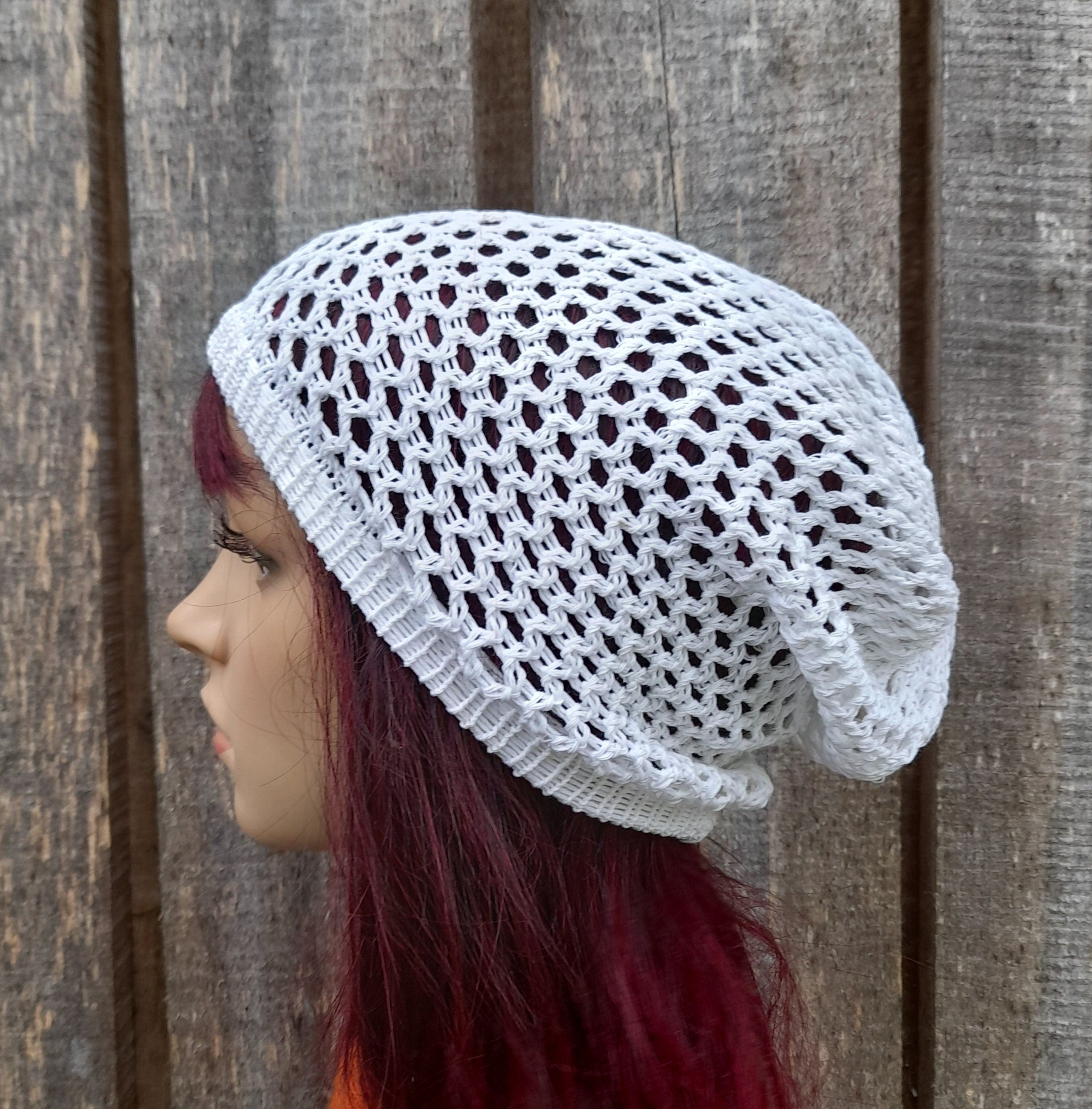 Person wearing a white knitted beanie against a wooden background