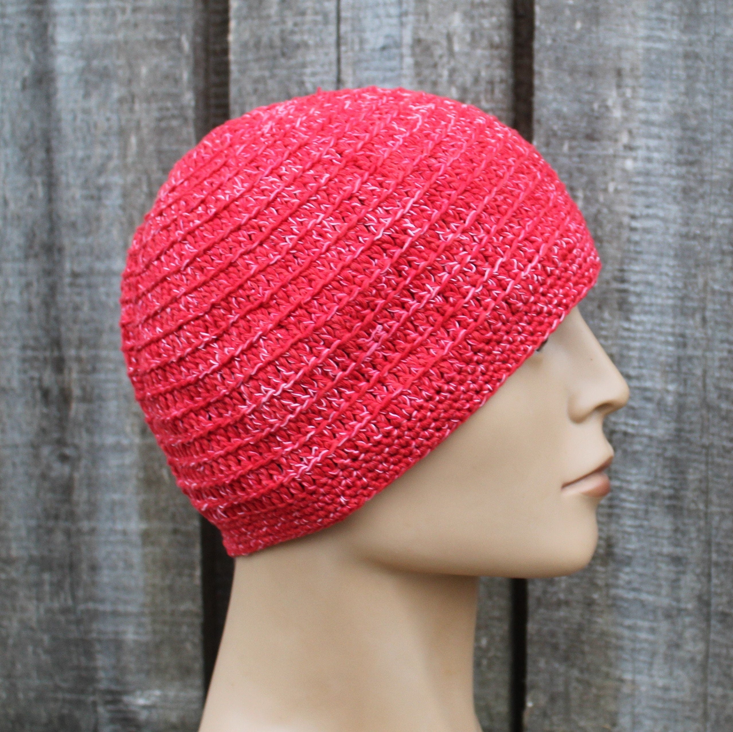 Red knitted beanie on a mannequin head against a wooden background