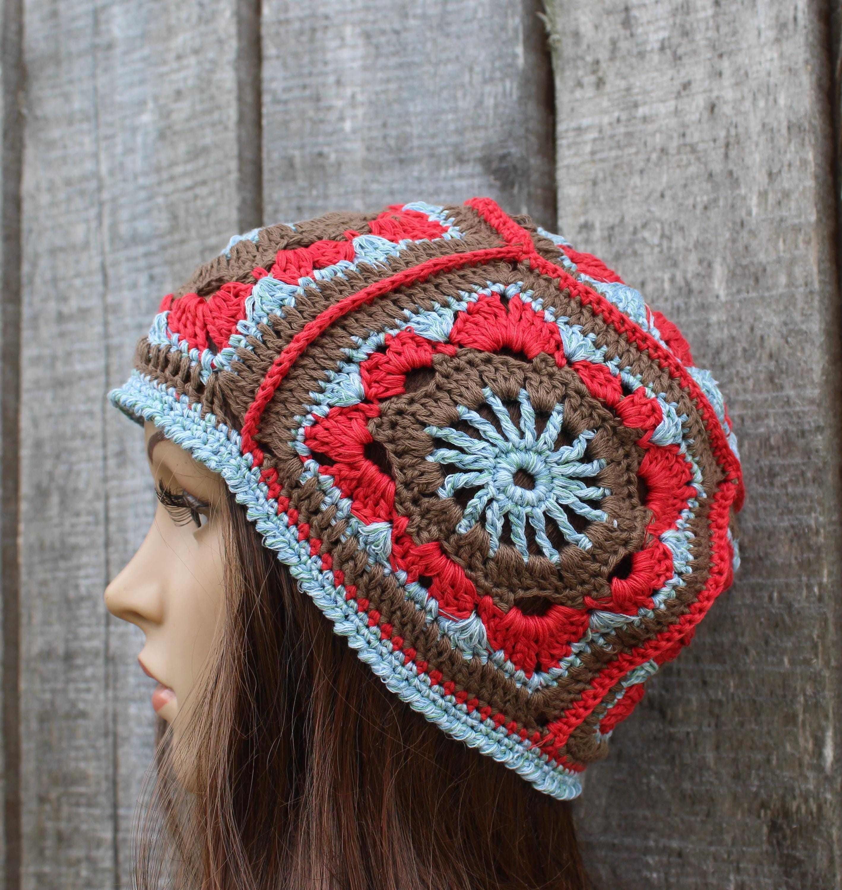 Crocheted beanie with red, brown, and blue pattern on a wooden background