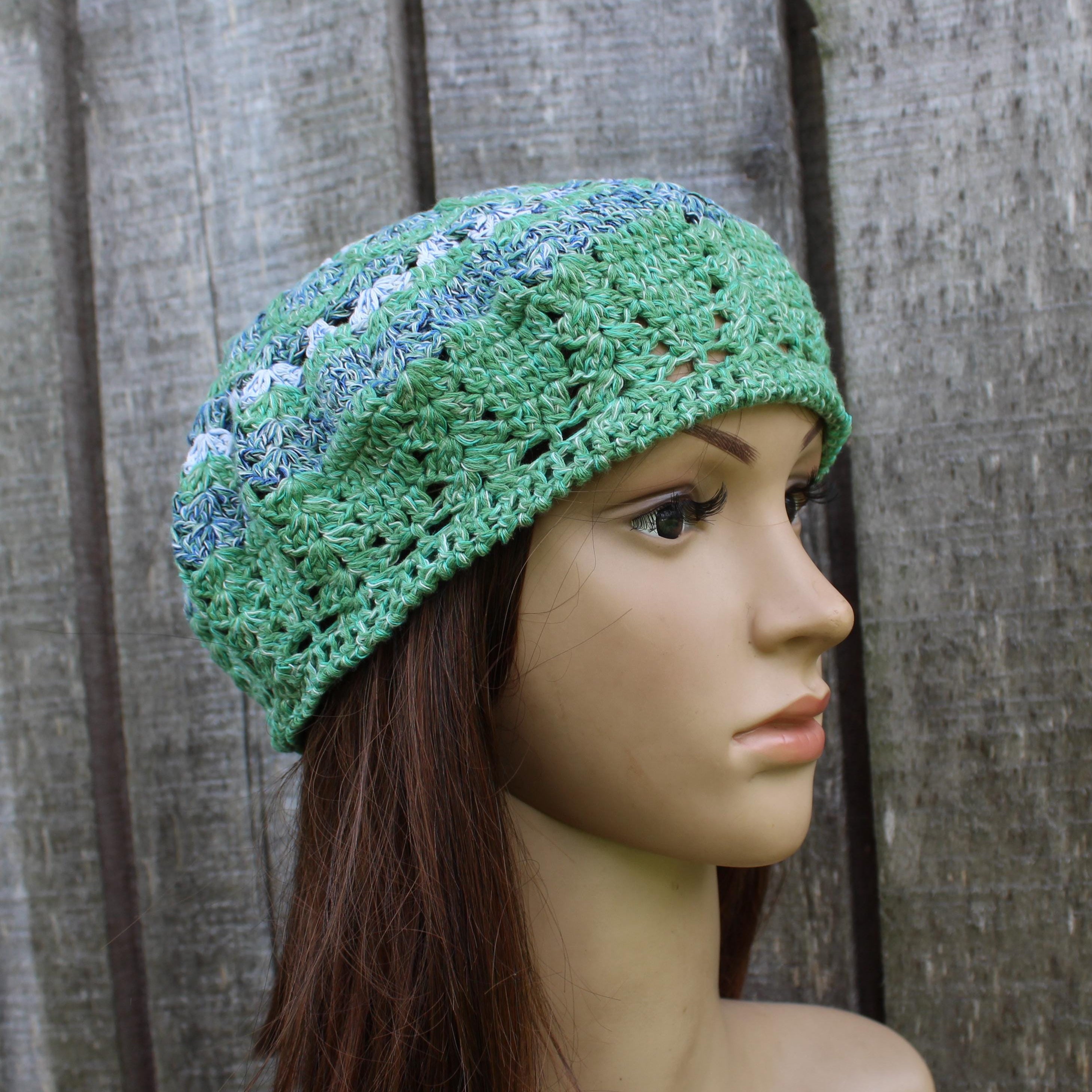 Green crocheted beanie on a mannequin head against a wooden background