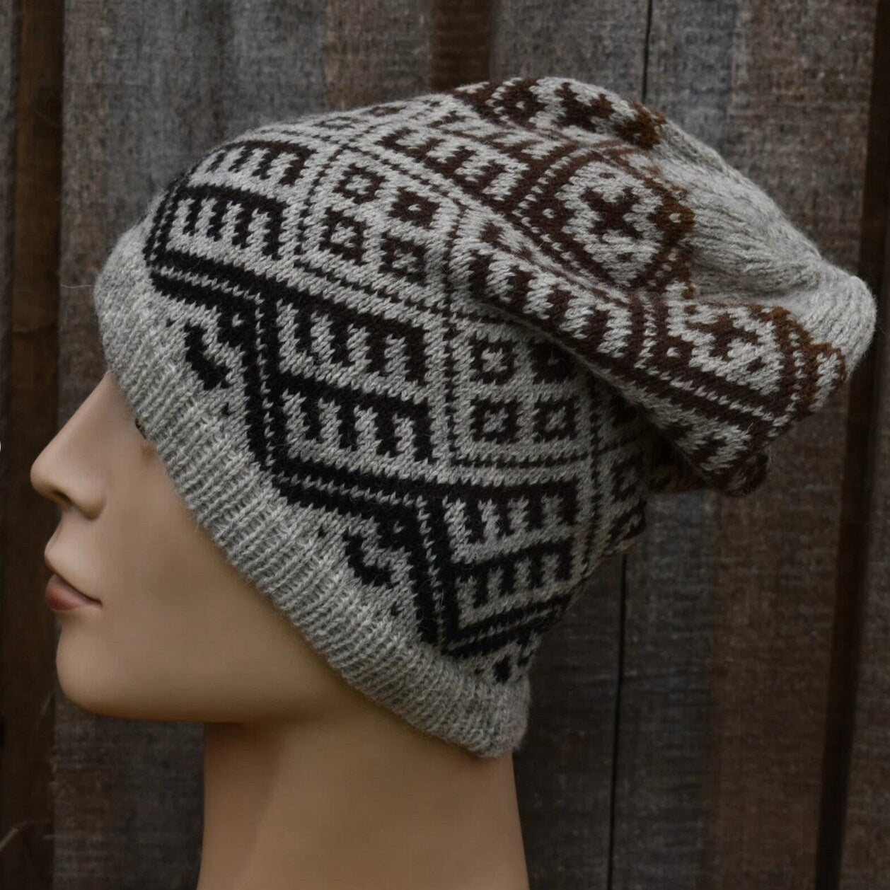 Knitted hat with a geometric pattern on a mannequin head against a wooden background