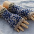 Pair of knitted fingerless gloves with blue and beige pattern on a light fabric background