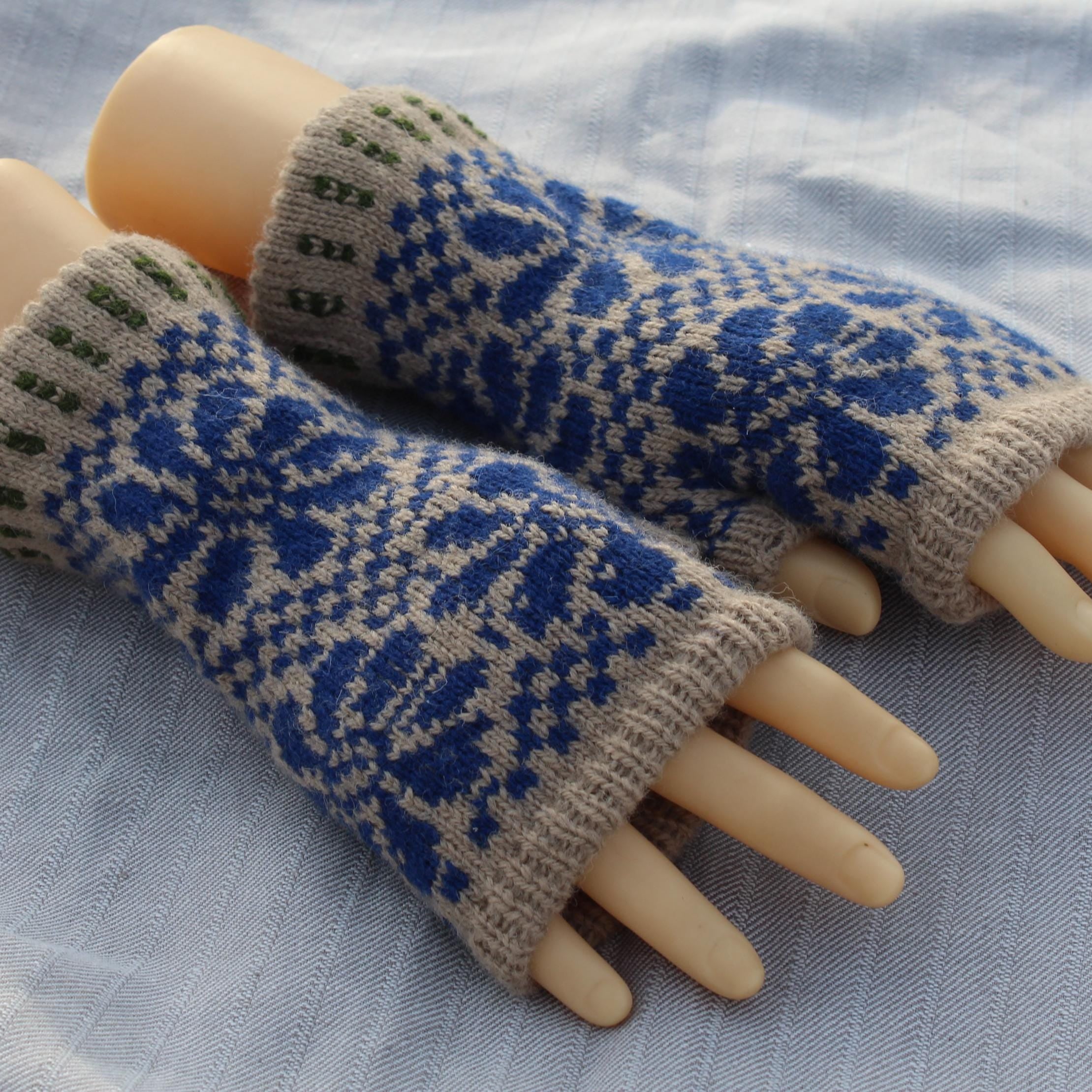 Pair of knitted fingerless gloves with blue and beige pattern on a light fabric background