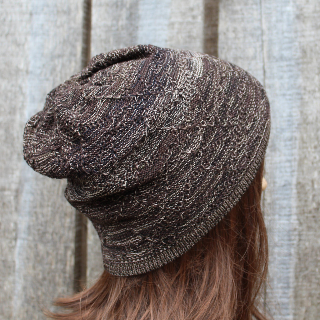 Brown knit beanie worn by a person with a neutral background