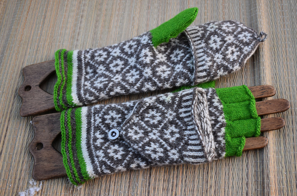 Pair of knitted mittens with green cuffs and tips on a wooden surface