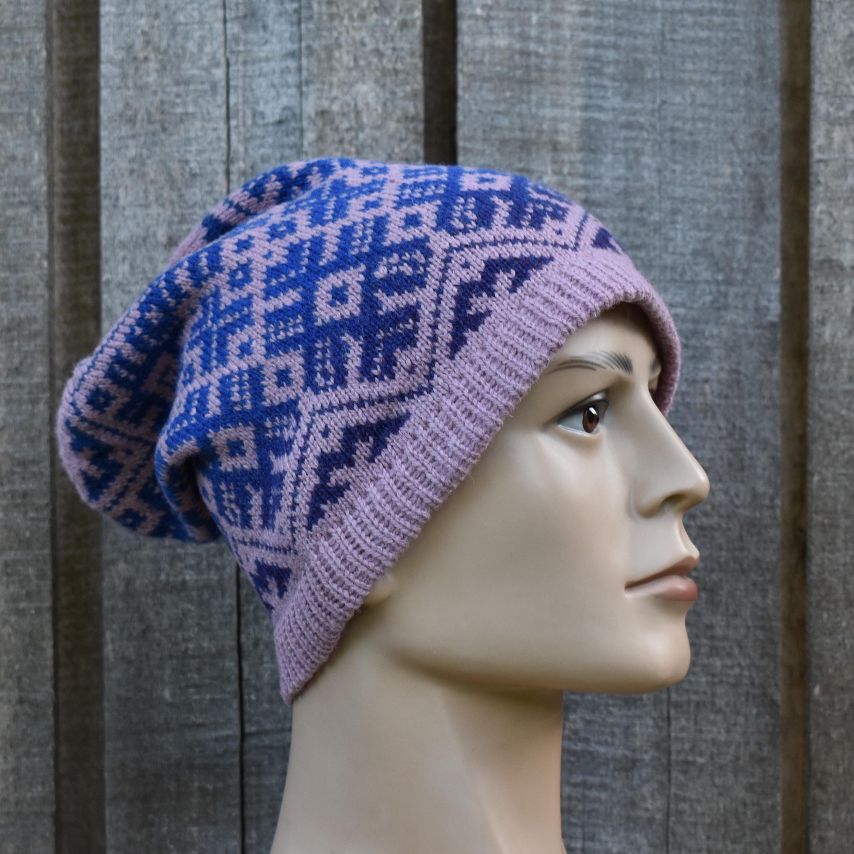 Mannequin head wearing a purple and blue patterned knit hat against a wooden background
