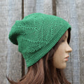 Green linen beanie on a mannequin head against a wooden background