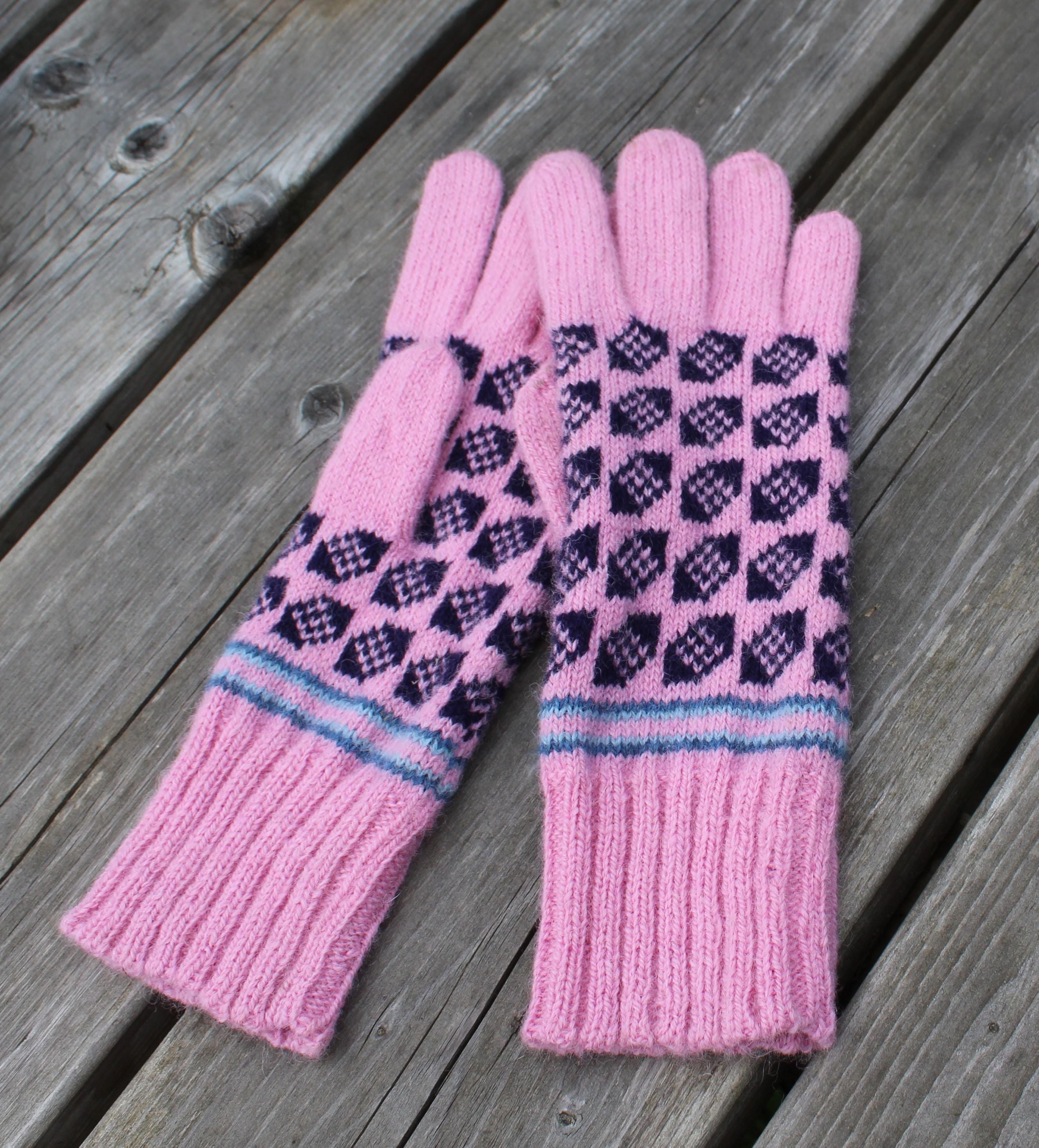Pair of pink gloves with a pattern on a wooden surface