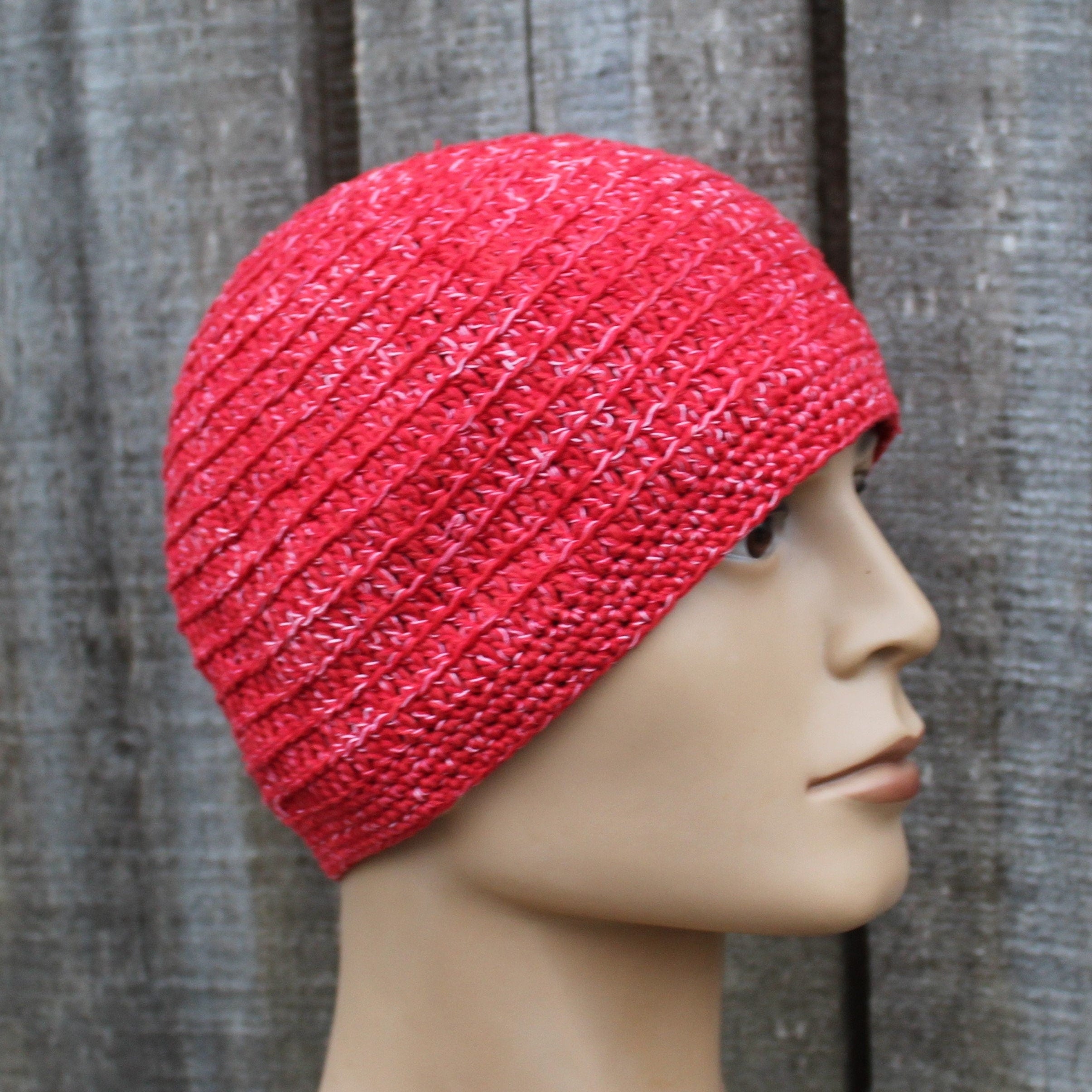 Red knitted beanie on a mannequin head against a wooden background