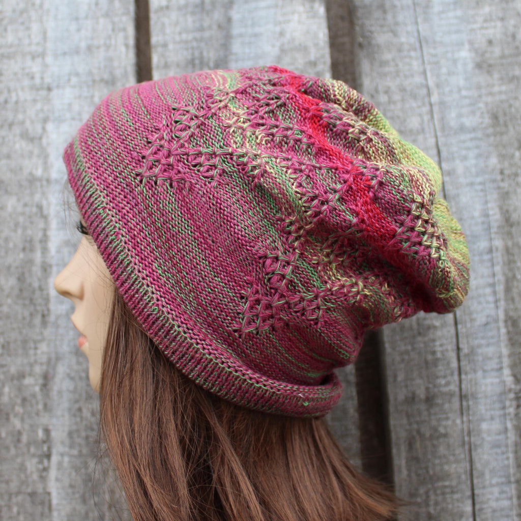 Knitted hat with a pink and green pattern worn by a person against a wooden background