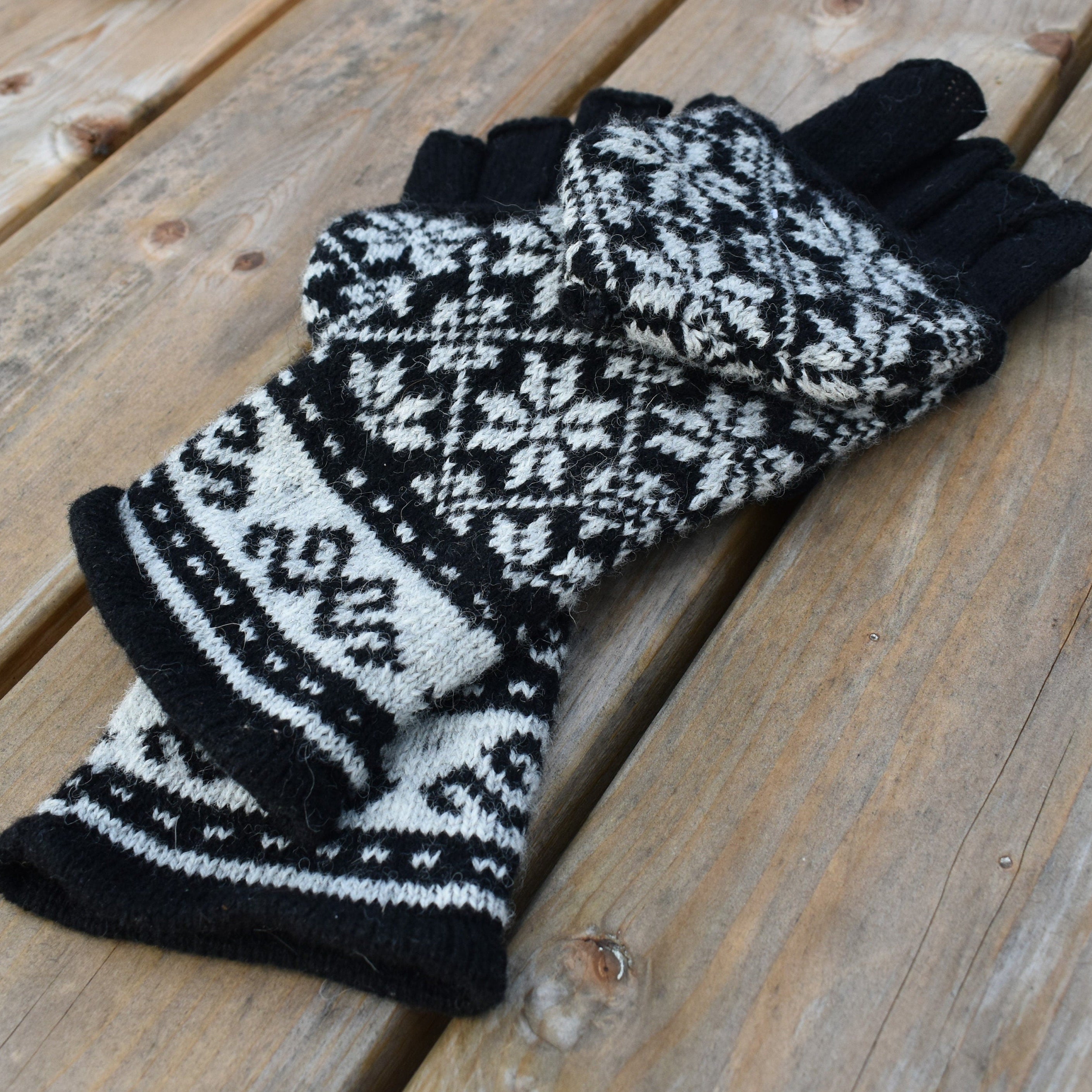 Pair of black and white patterned gloves on a wooden surface