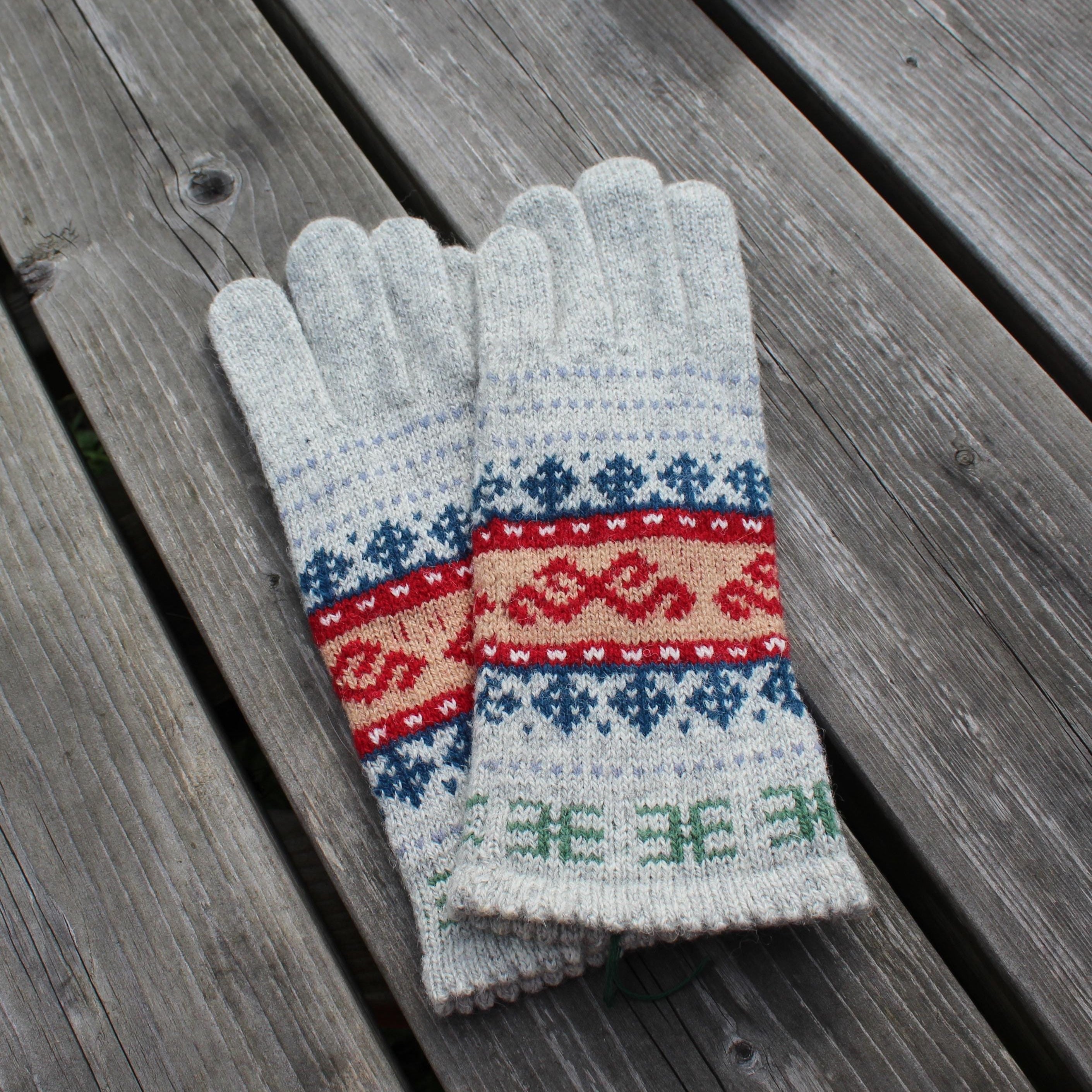 Pair of gray gloves with colorful fair Isle patterns on a wooden surface