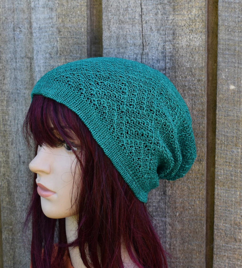 Teal knitted beanie on a mannequin head against a wooden background