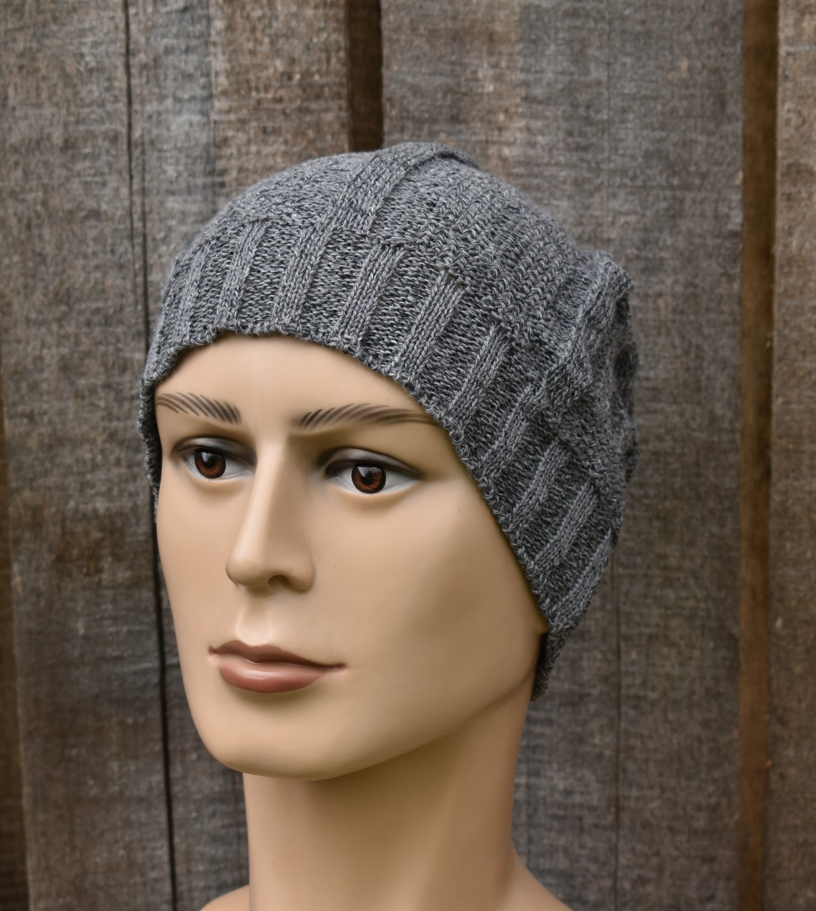 Gray knitted beanie on a mannequin head against a wooden background
