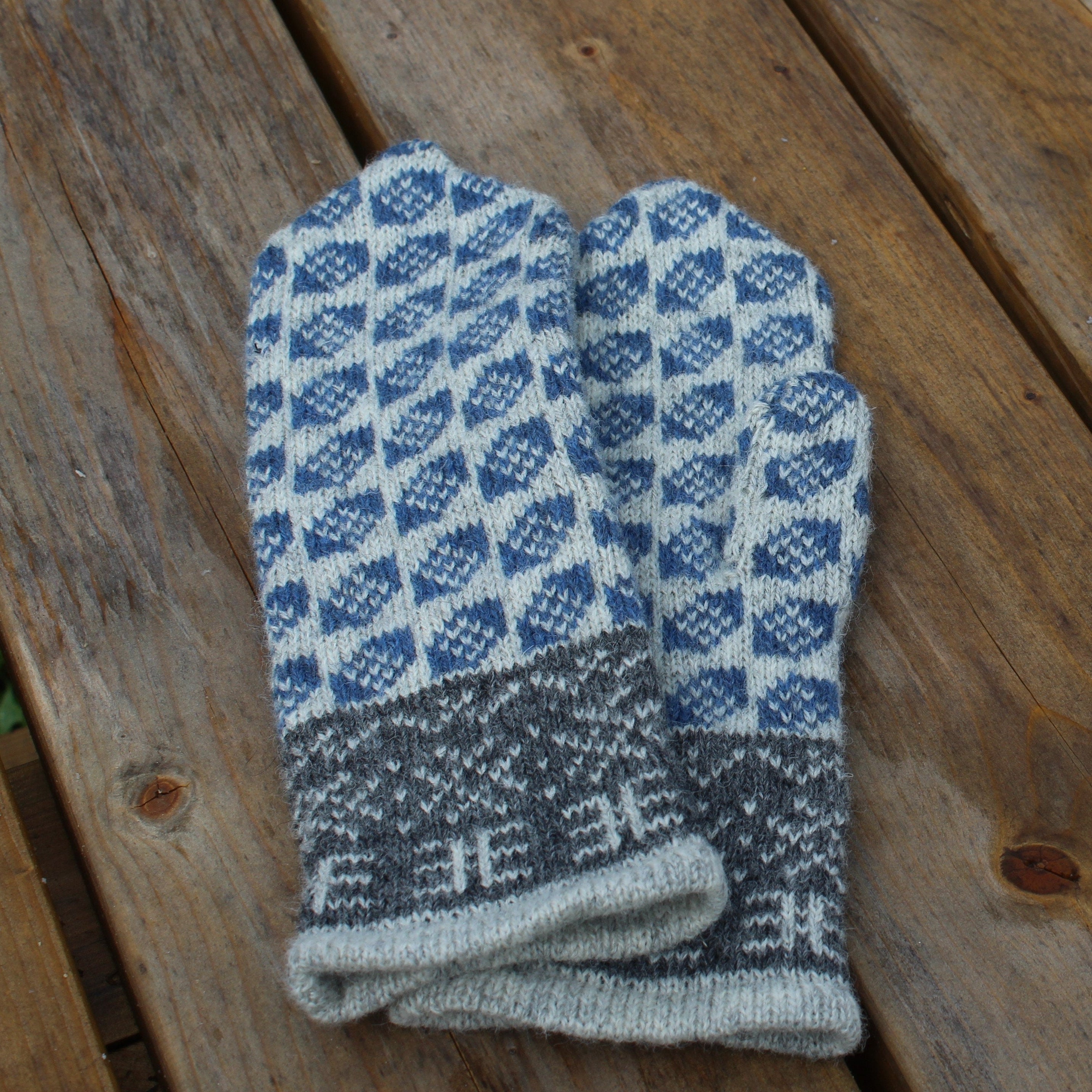 Pair of blue and gray checkered mittens on a wooden surface