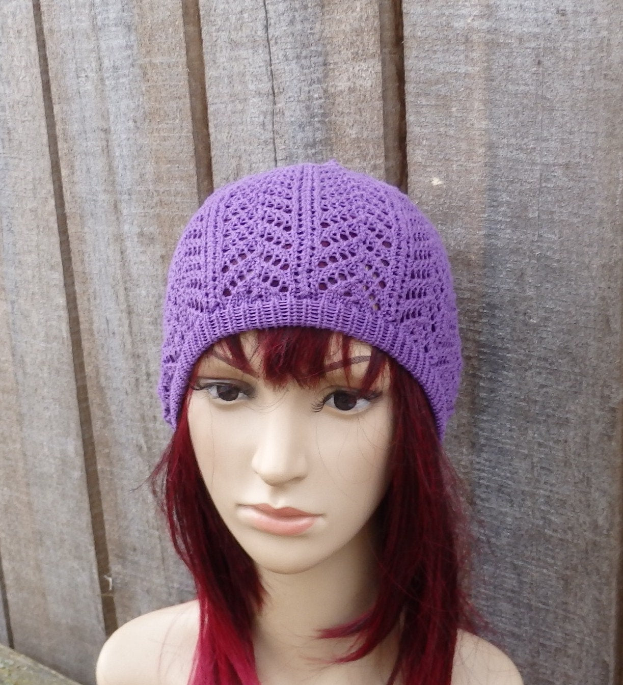 Purple knitted beanie on a mannequin head against a wooden background