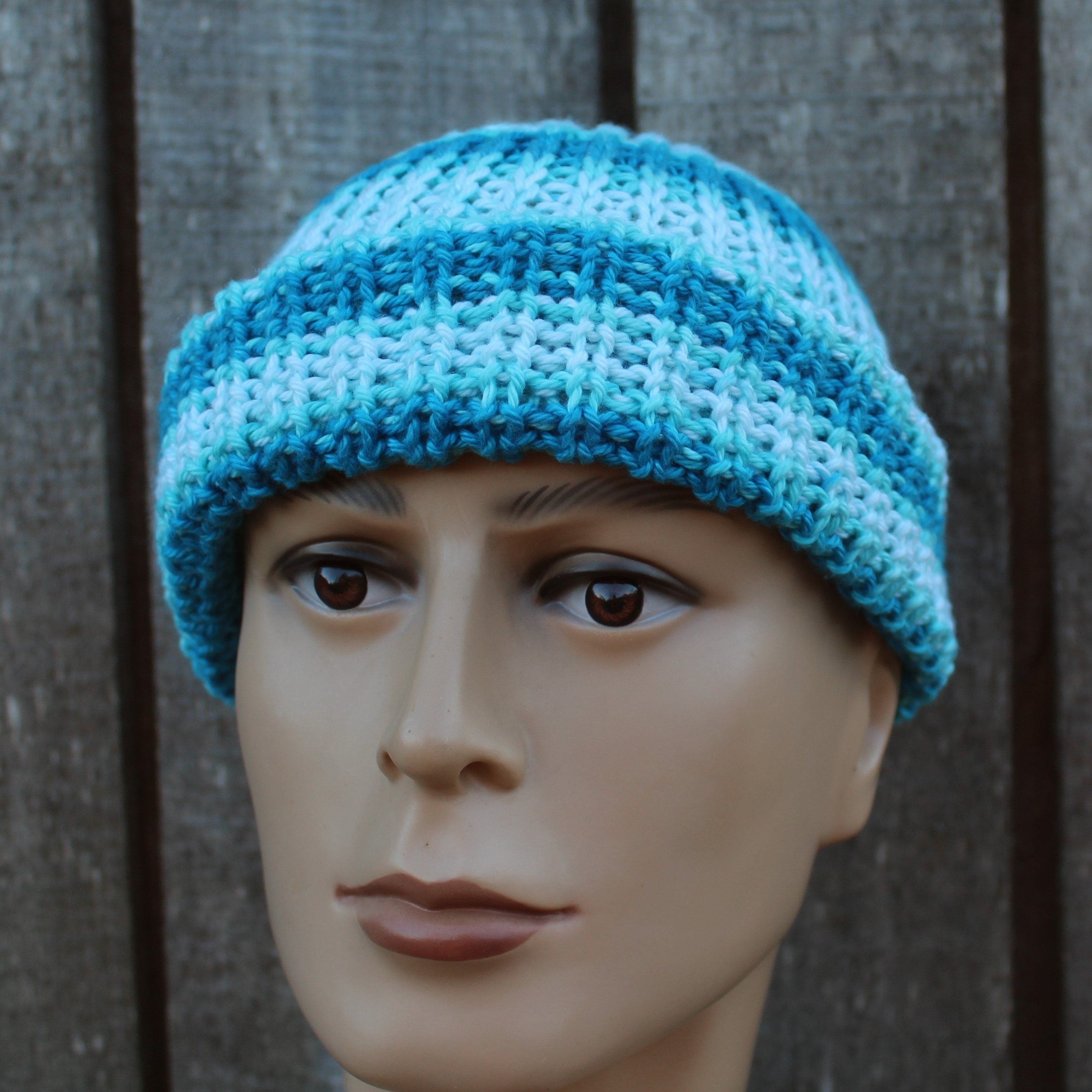 Blue knitted beanie on a mannequin head against a wooden background