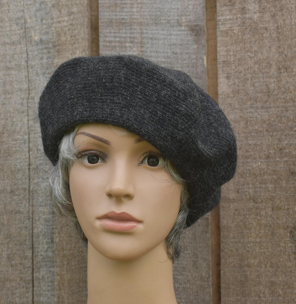 Dark gray beret on a mannequin head against a wooden background
