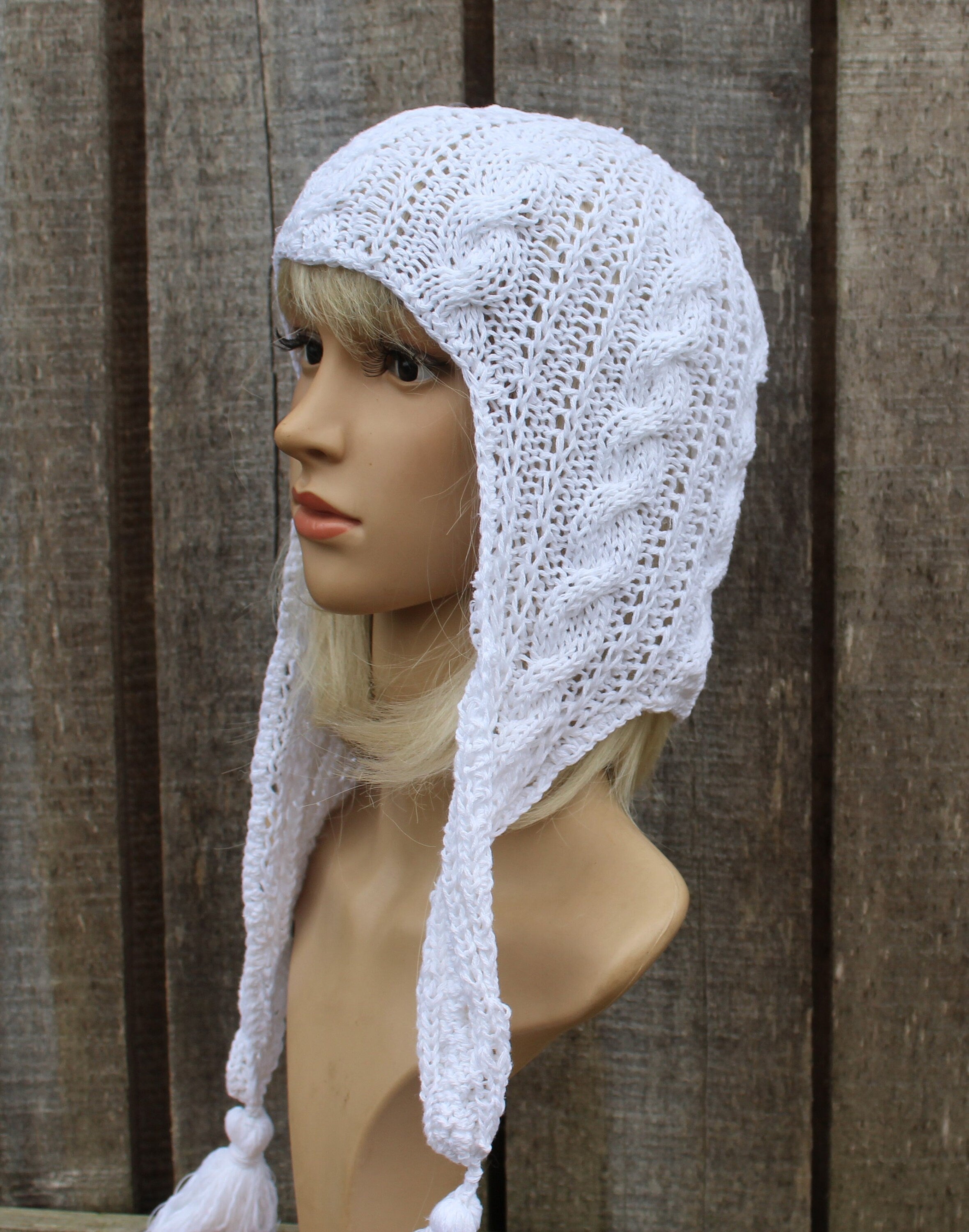 White knitted bonnet on a mannequin head against a wooden background
