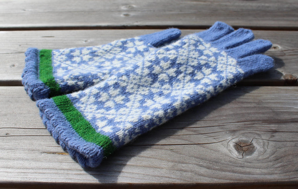 Pair of blue and white patterned gloves with green accents on a wooden surface