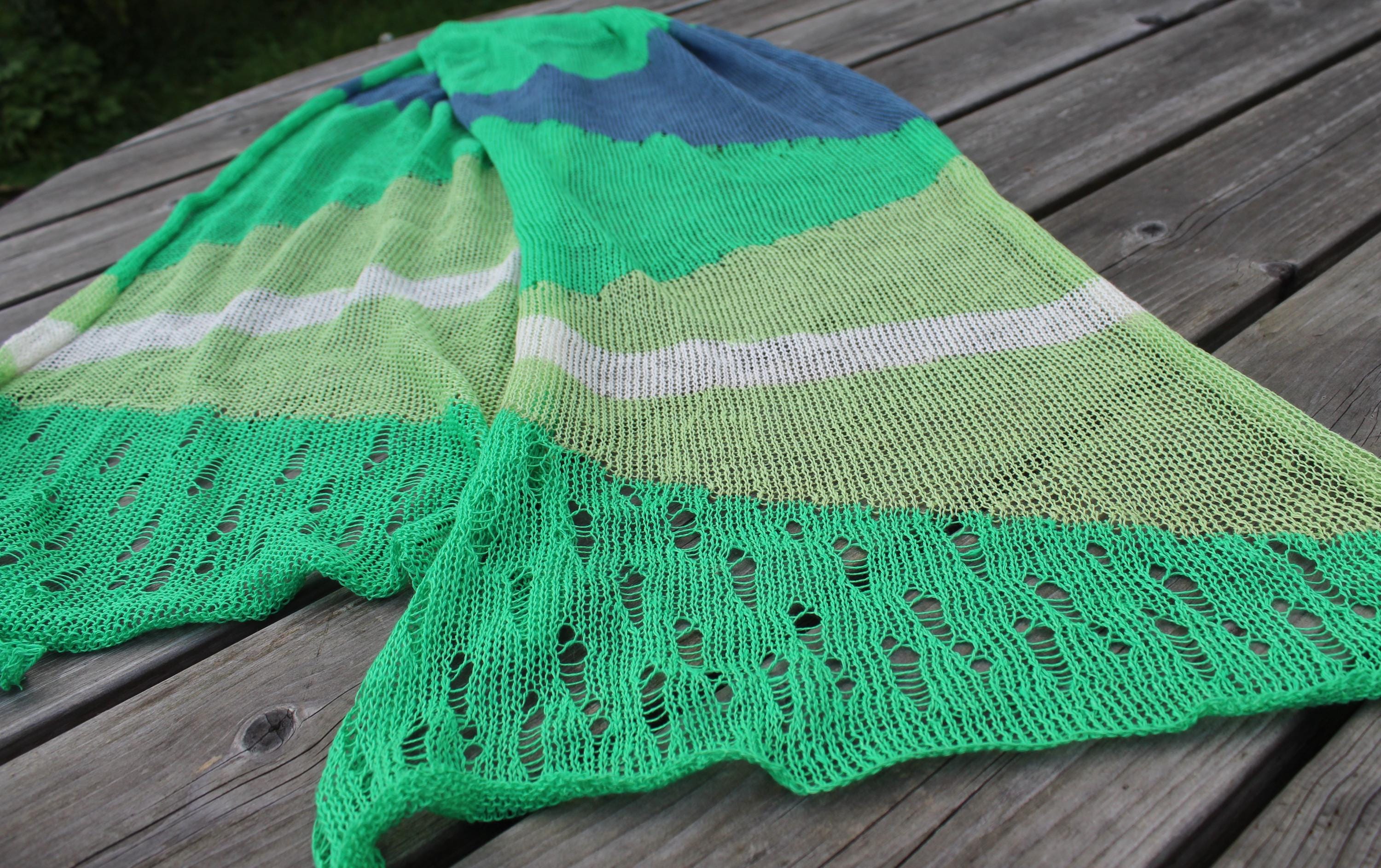Green knitted shawl with lace edge on a wooden surface