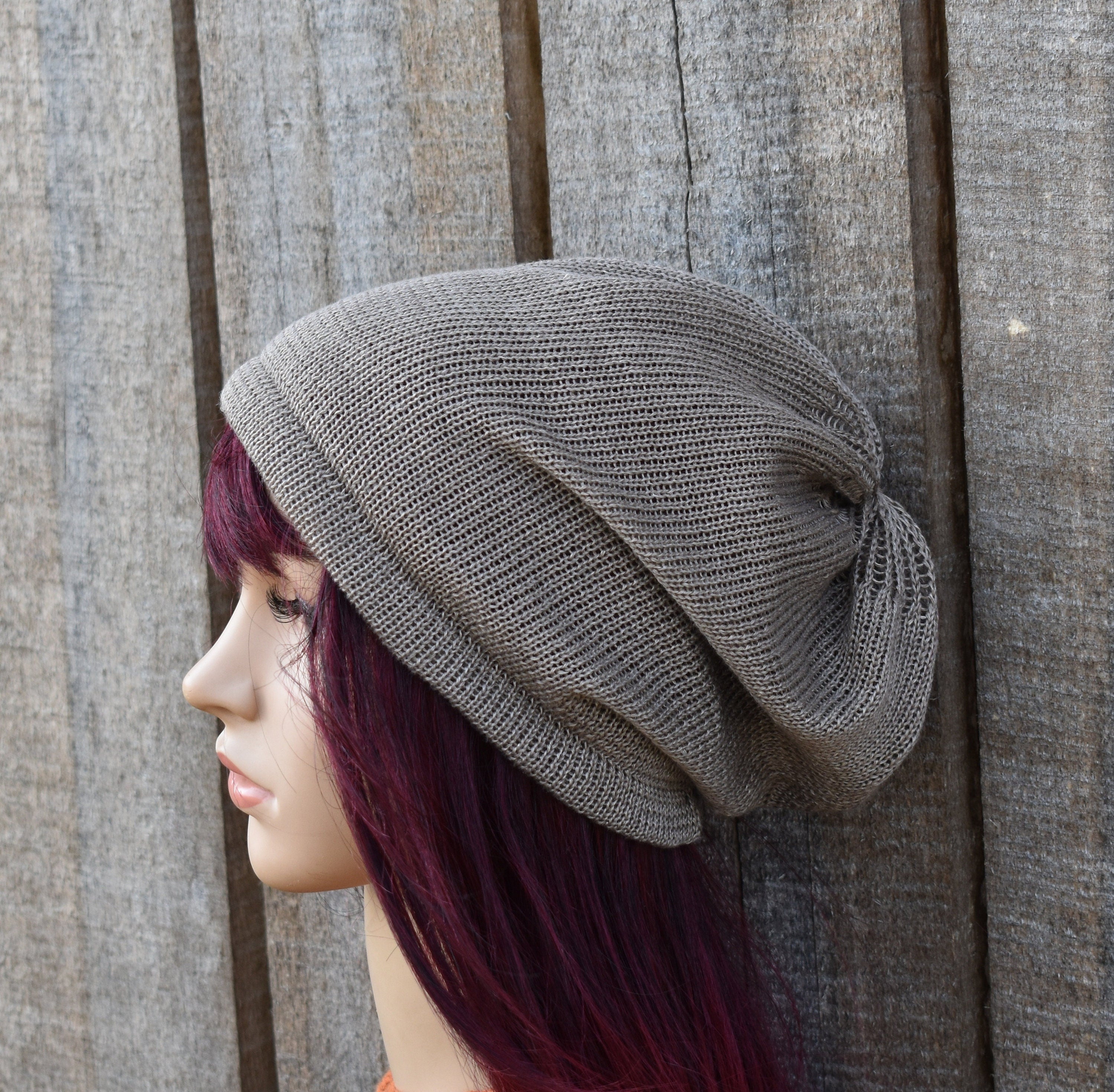 Person wearing a gray knit beanie against a wooden background