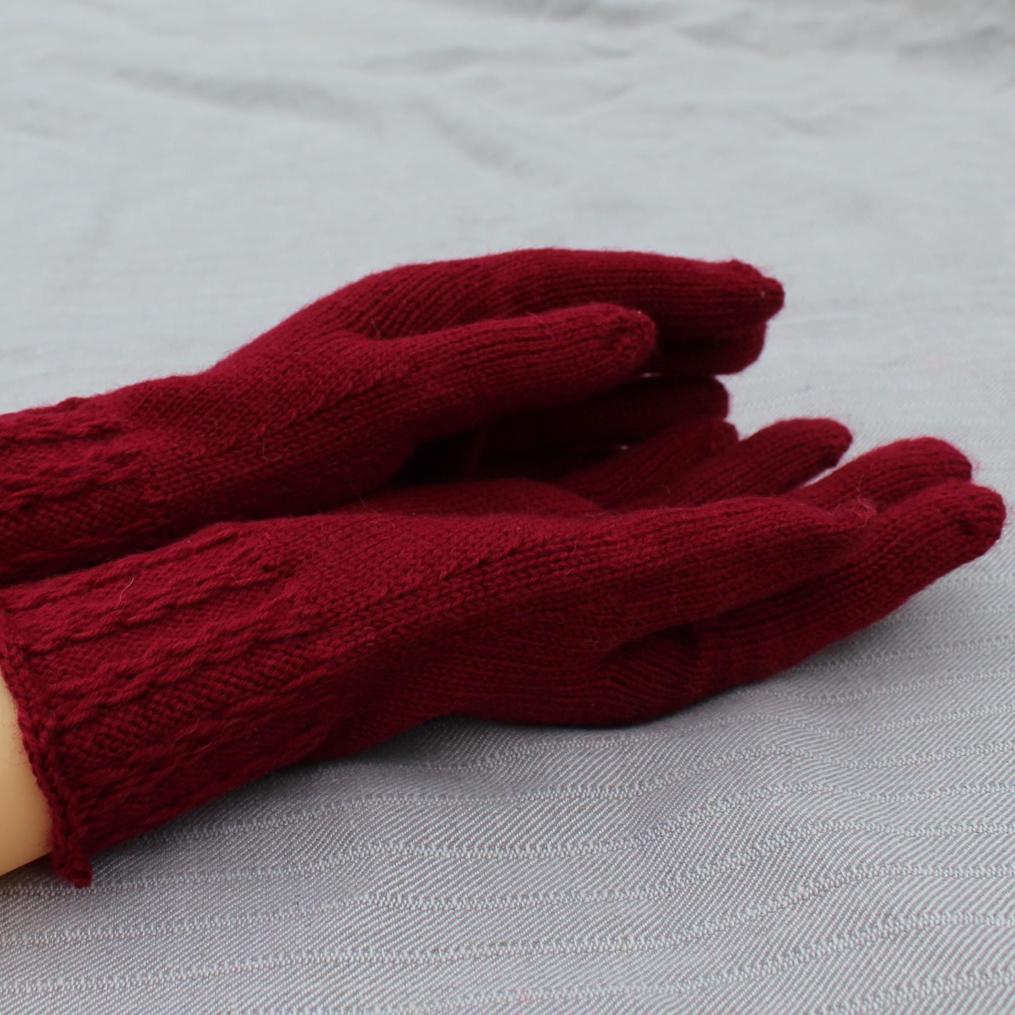 Pair of red gloves on a mannequin hand against a light gray background