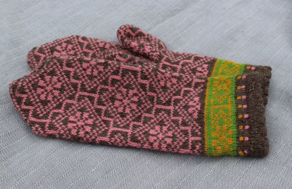 Knitted gloves with a pink and brown pattern on a gray fabric background