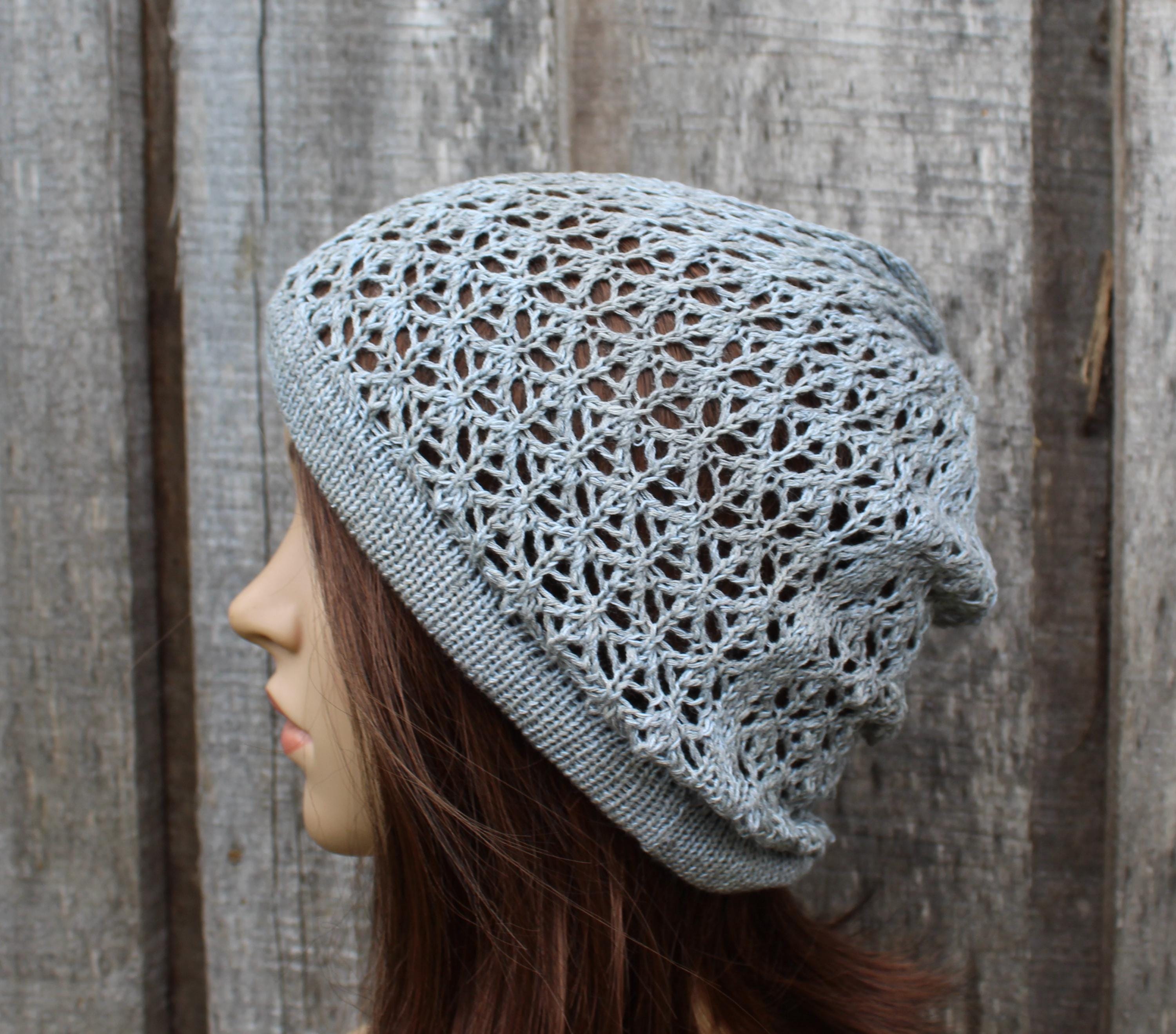 Person wearing a light gray knitted beanie against a wooden background