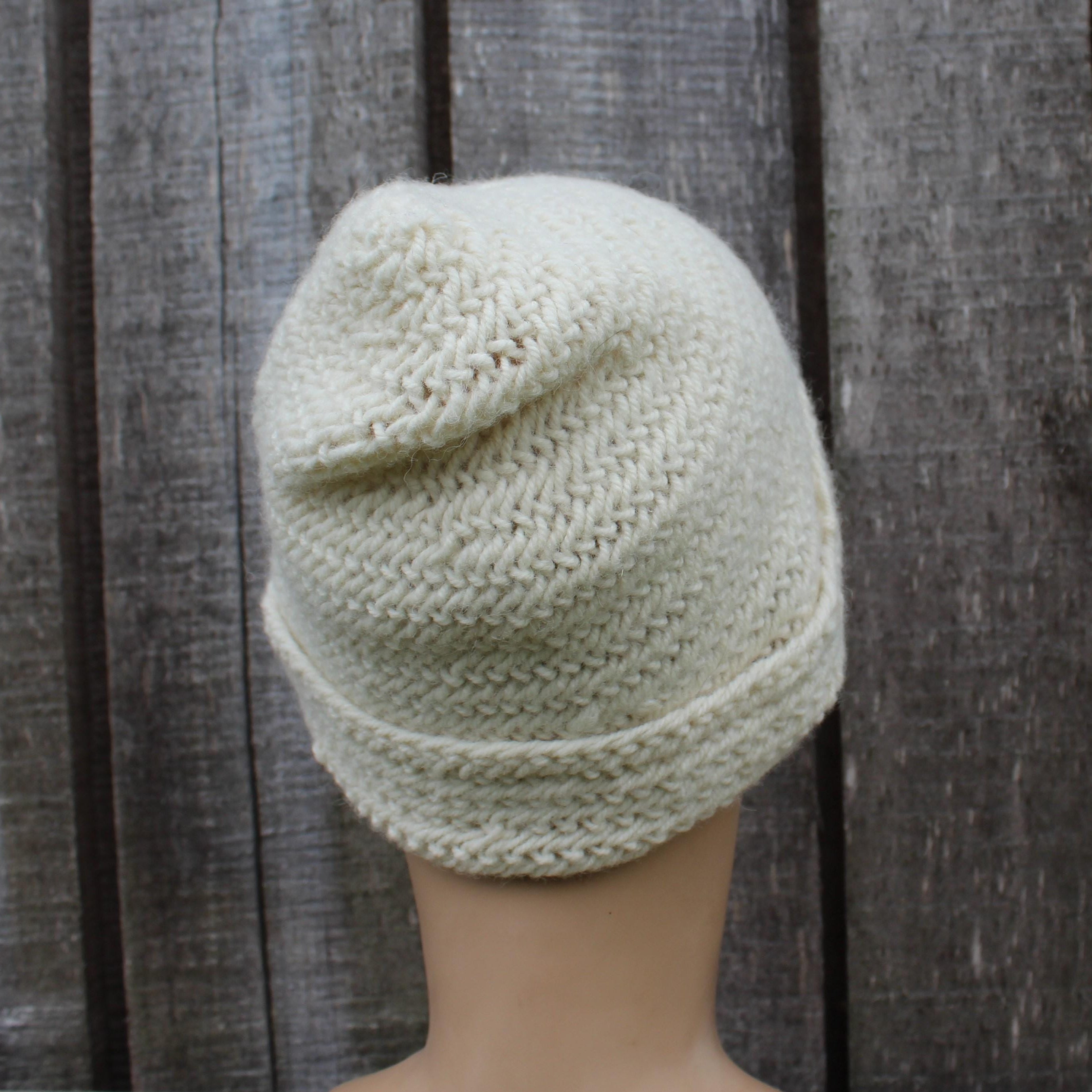 Needle binding beanie on a mannequin head against a wooden background