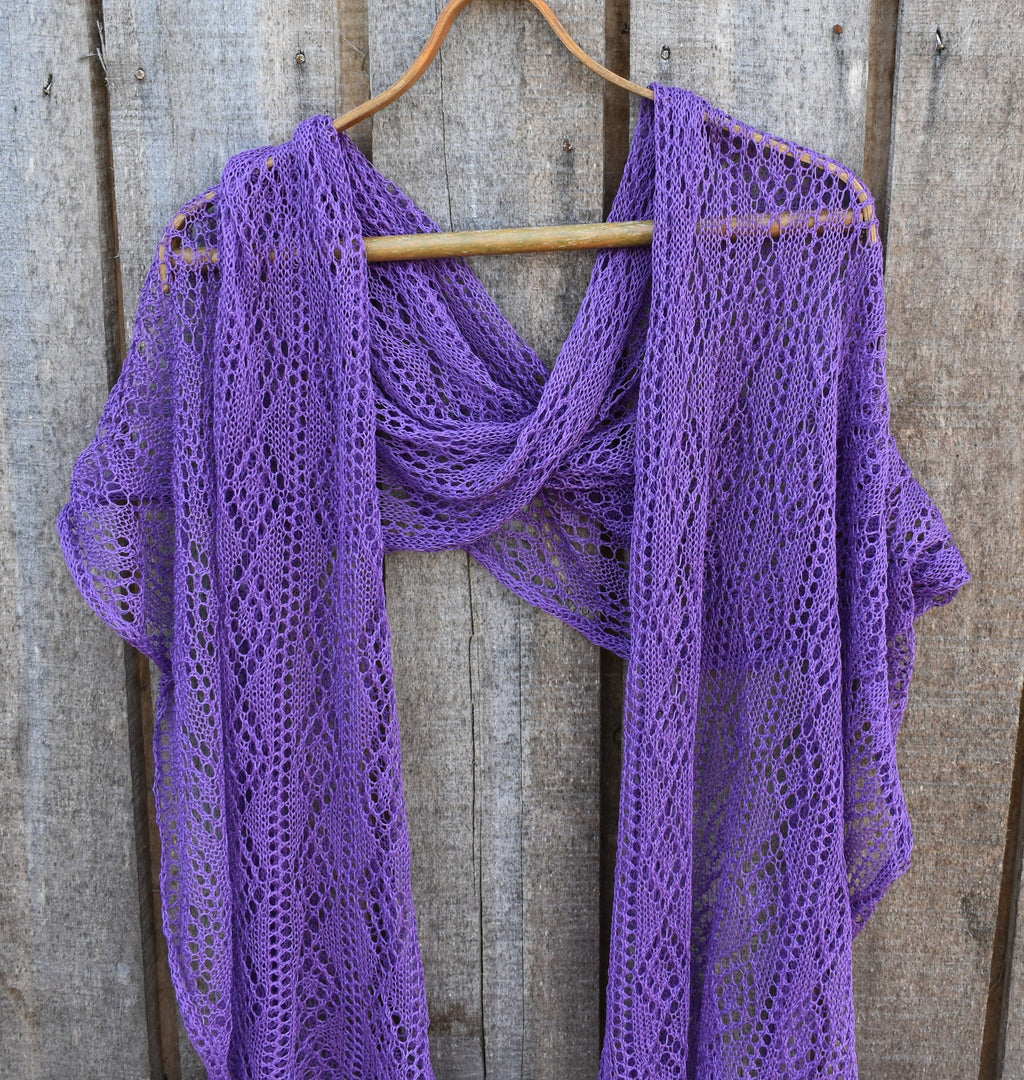 Purple knitted shawl on a wooden hanger against a wooden background