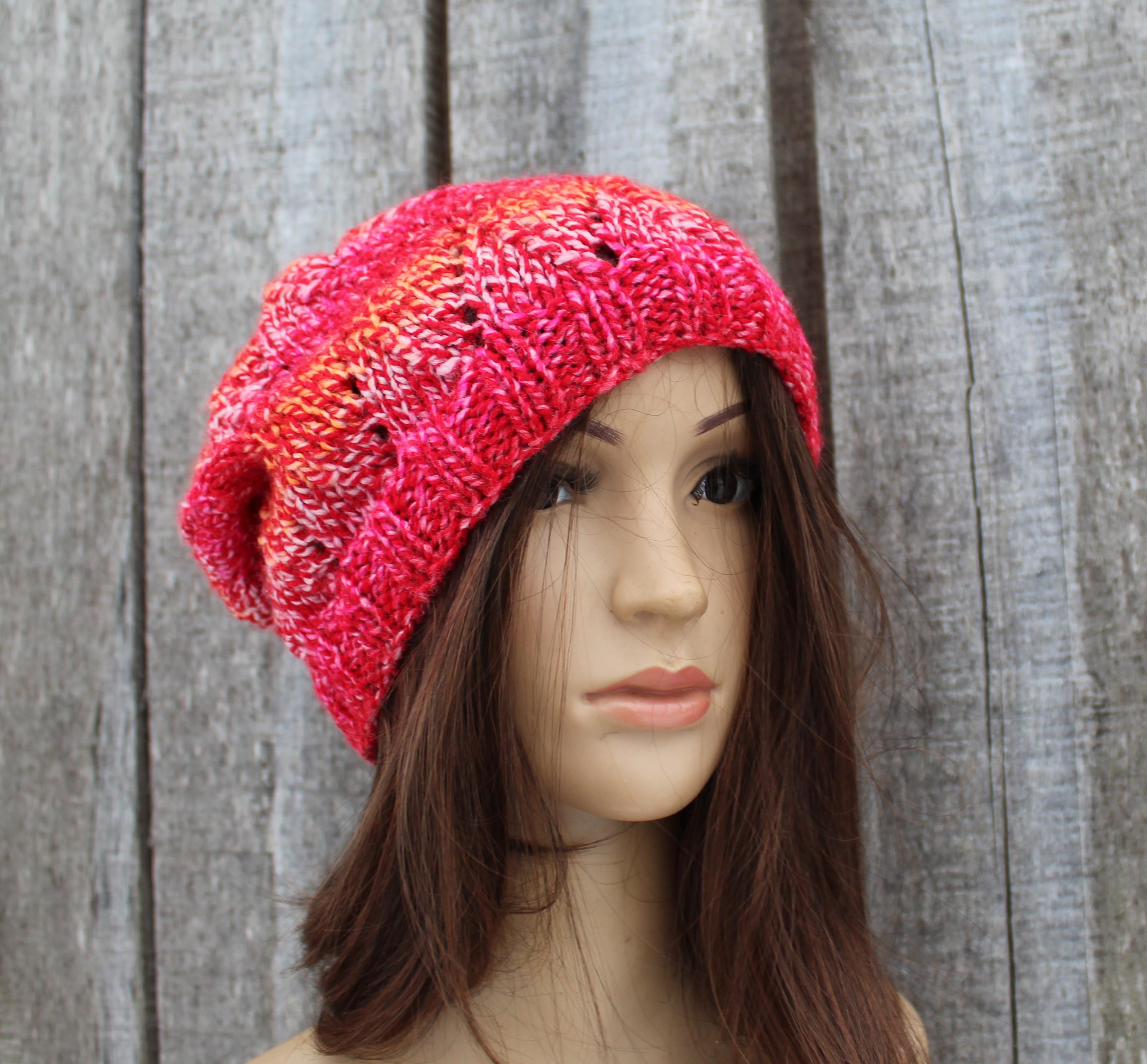 Mannequin head wearing a bright pink knitted beanie against a wooden background