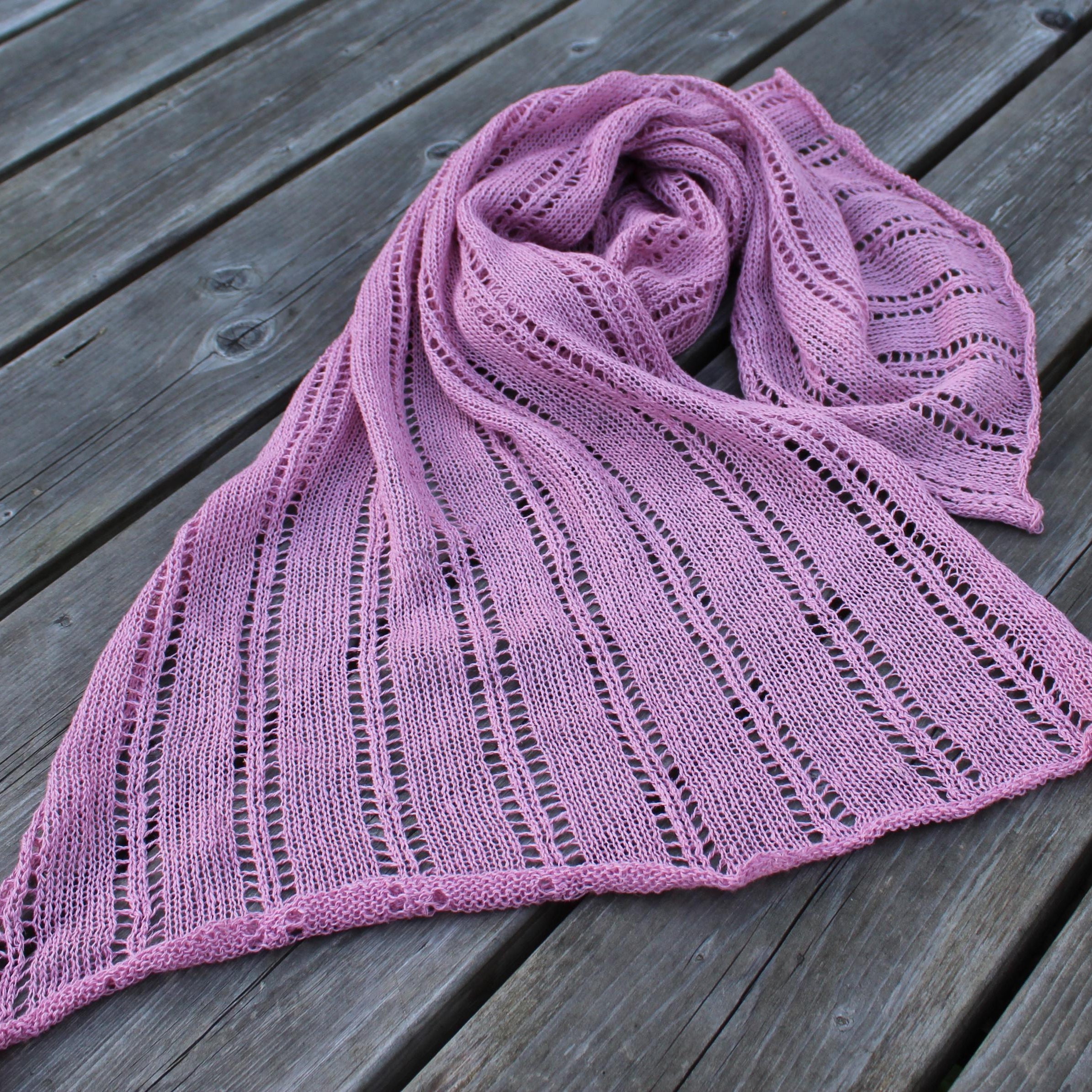 Pink knitted shawl on a wooden surface