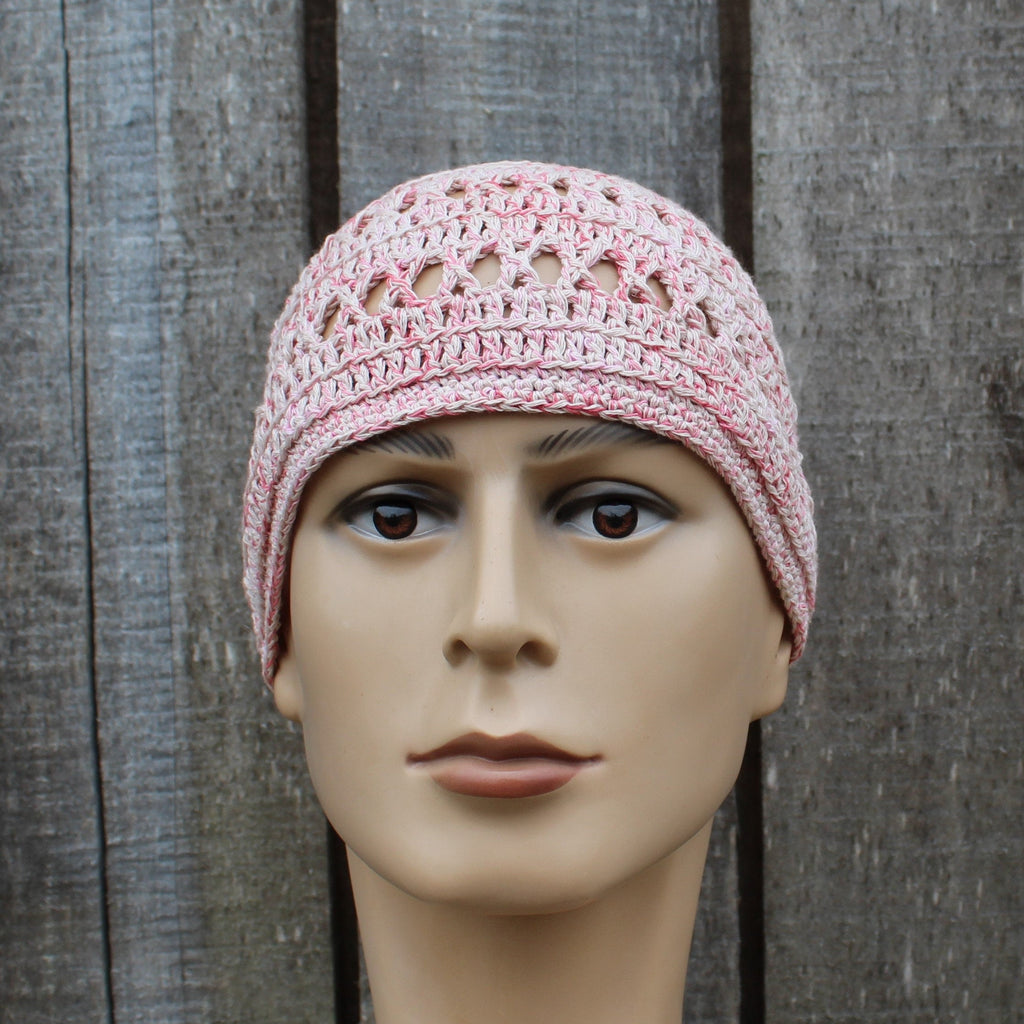 Mannequin head wearing a pink crochet beanie against a wooden background