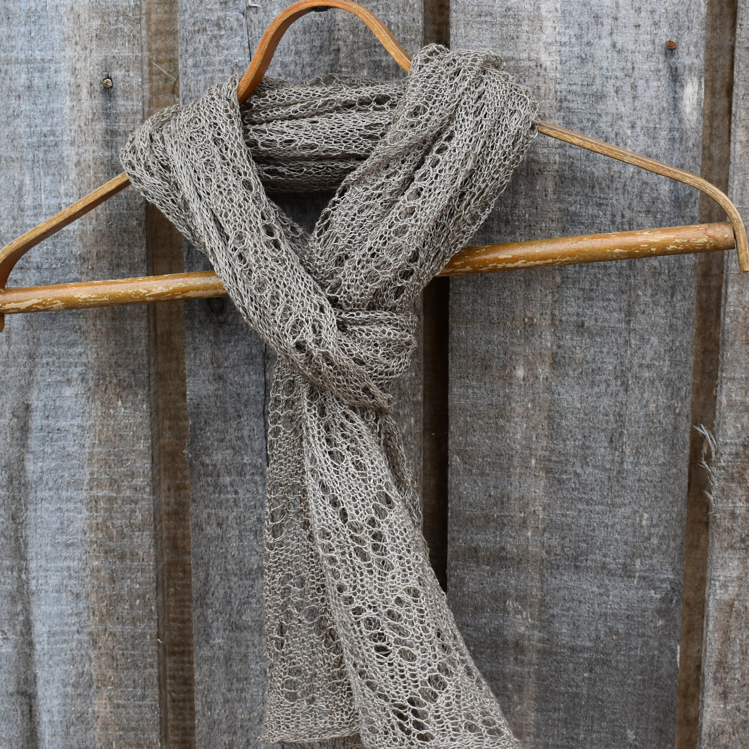 Knitted scarf on a wooden hanger against a rustic metal background