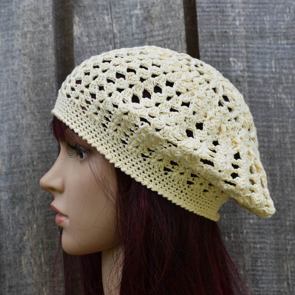 Crocheted beige hat on a mannequin head against a wooden background
