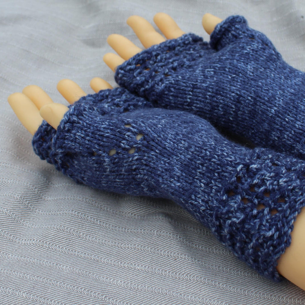 Blue knitted fingerless gloves on a mannequin hand against a gray background