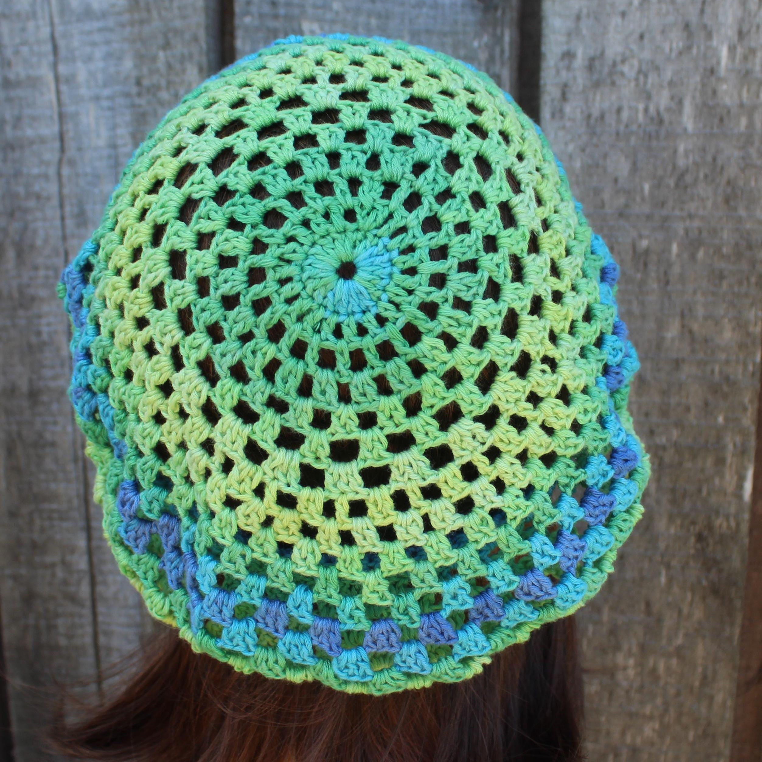 Crocheted hat with green and blue pattern against a wooden background