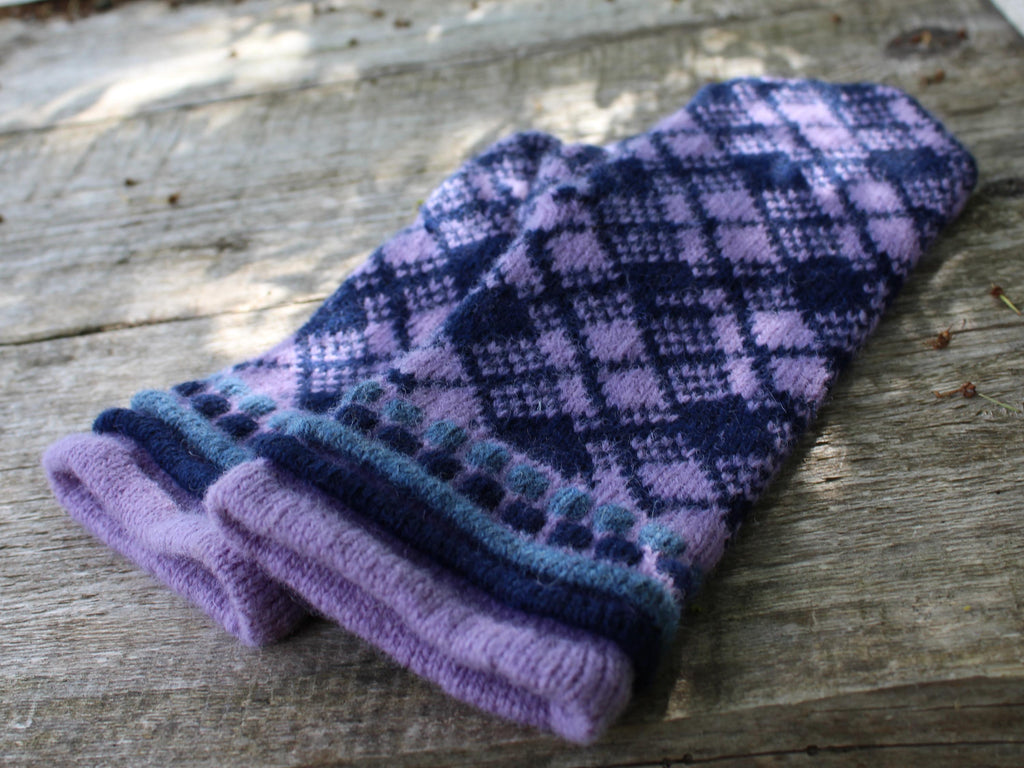 Pair of purple and blue checkered mittens on a wooden surface