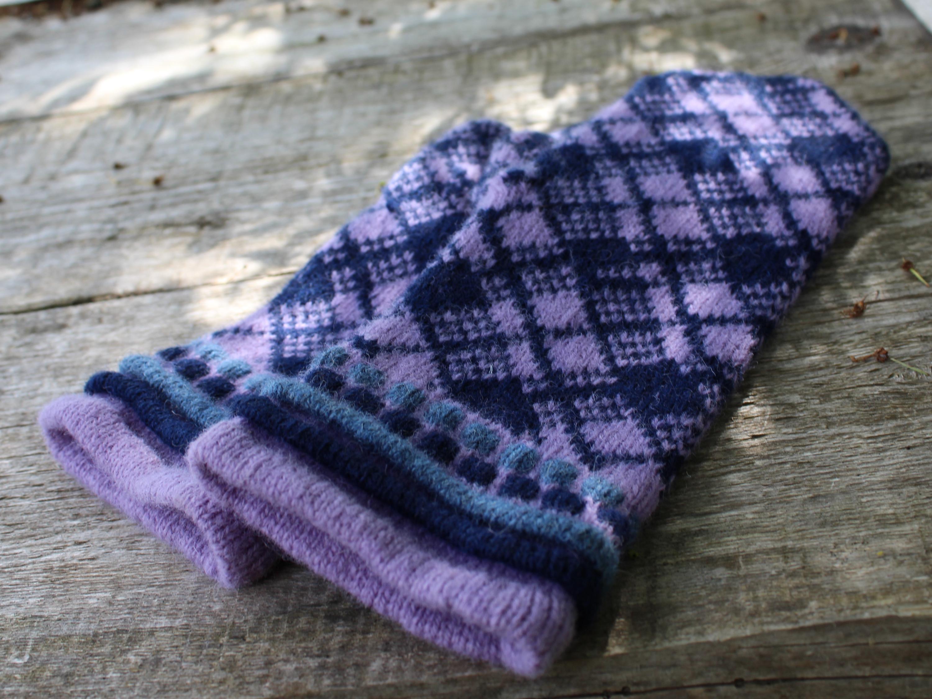 Pair of purple and blue checkered mittens on a wooden surface
