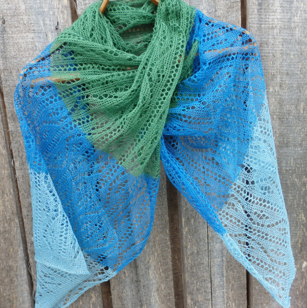 Knitted shawl with green and blue gradient on a wooden background