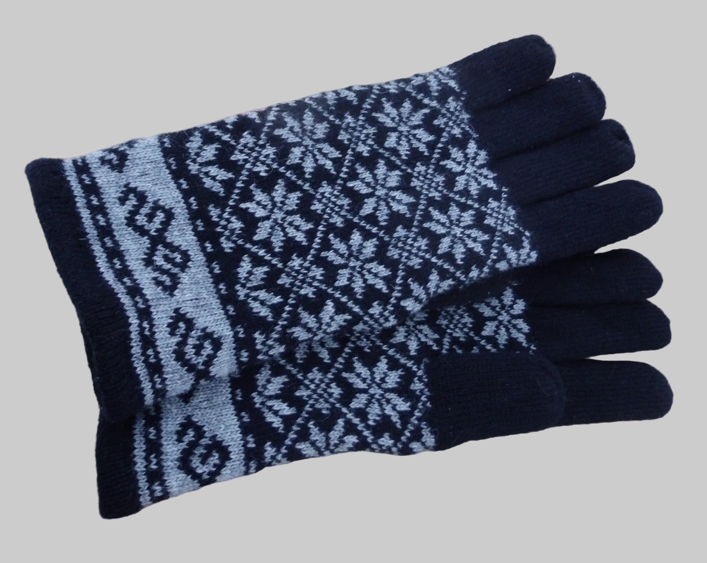 Black and gray patterned glove on a wooden stick against a wooden background