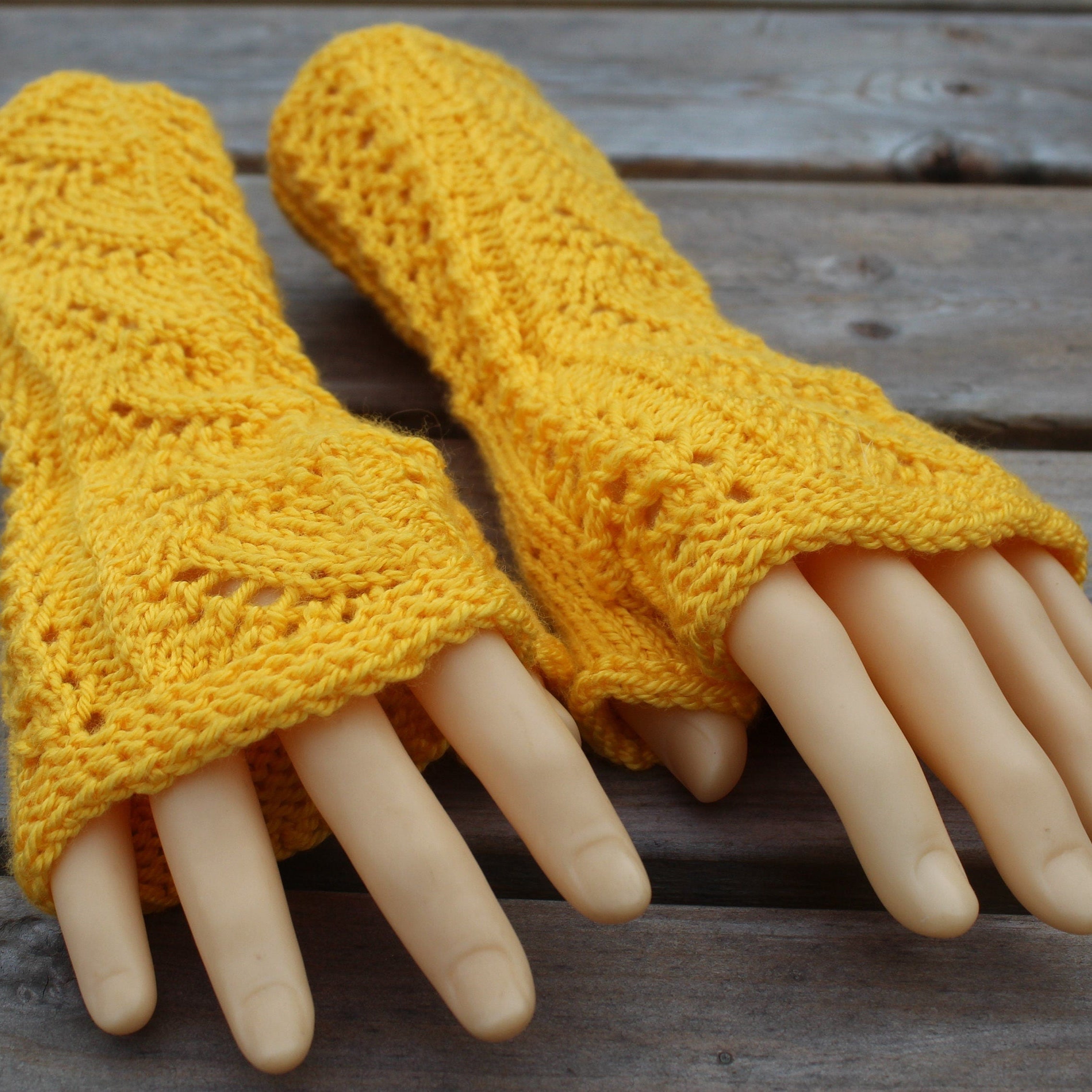 Yellow knitted fingerless gloves on a wooden surface