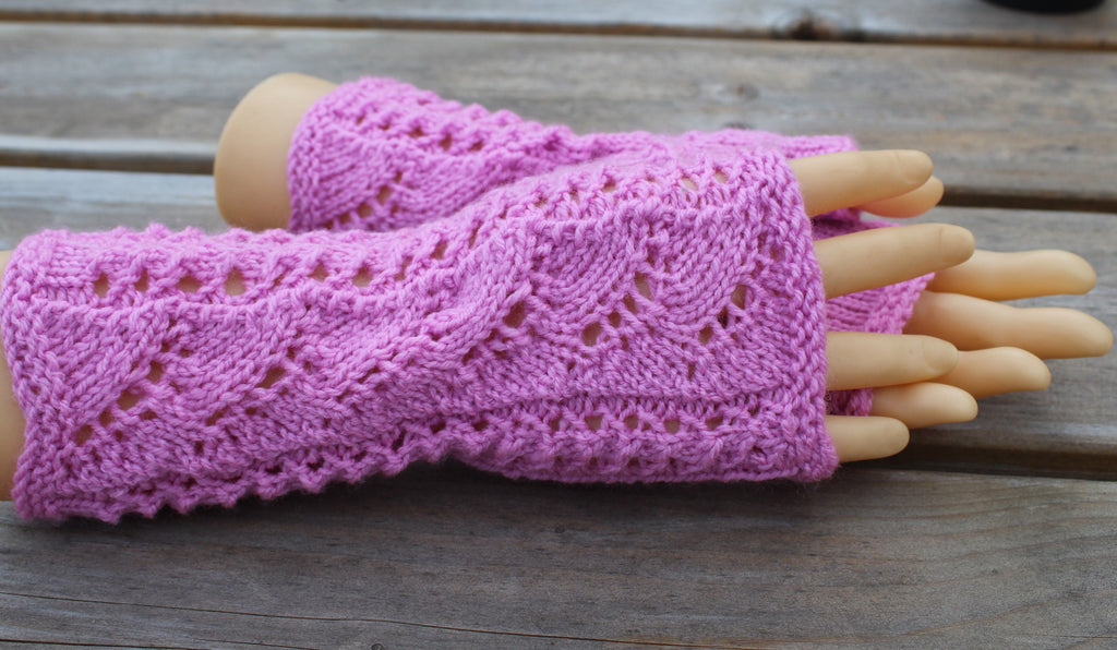 Pink knitted fingerless gloves on a wooden surface