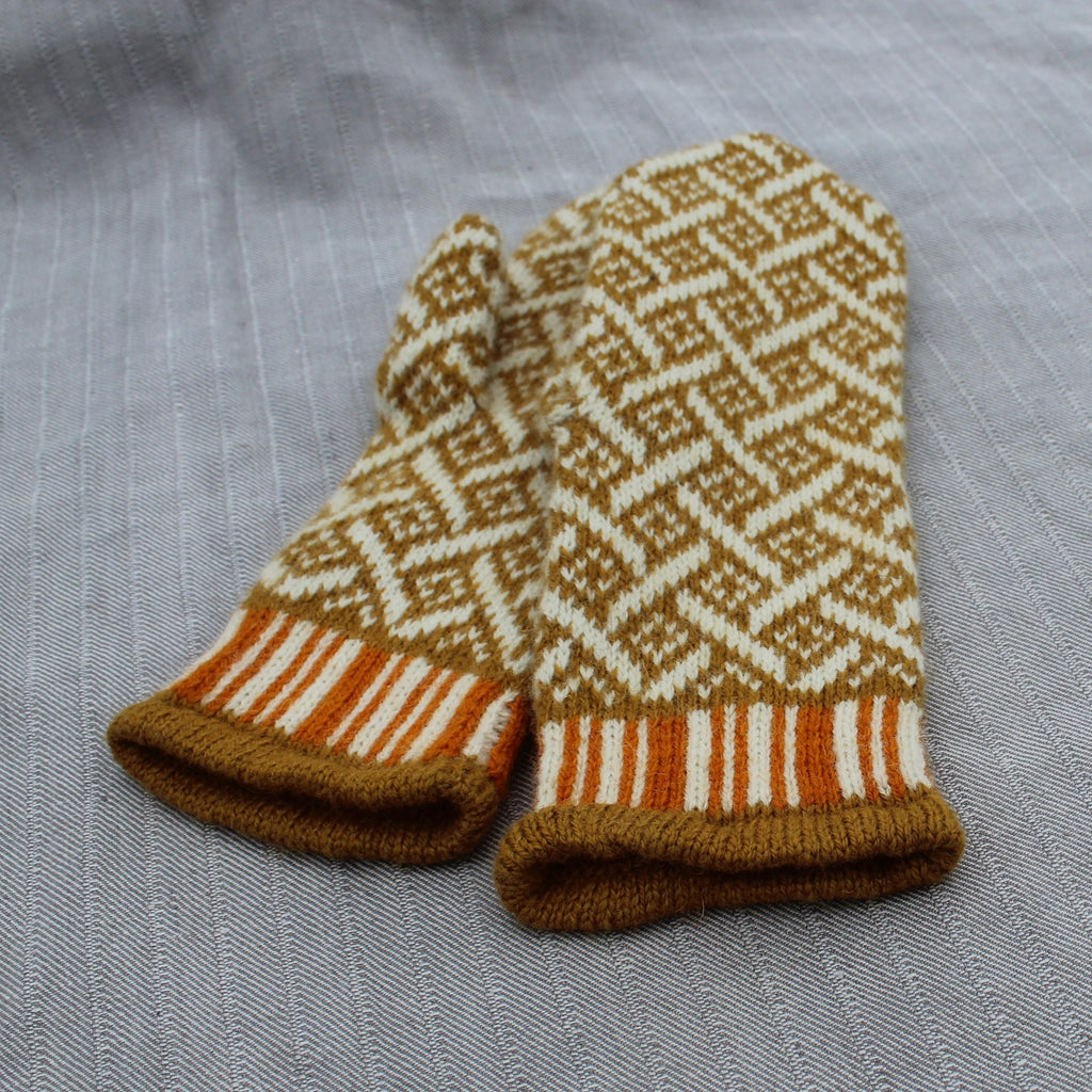 Pair of knitted mittens with a geometric pattern on a gray fabric background