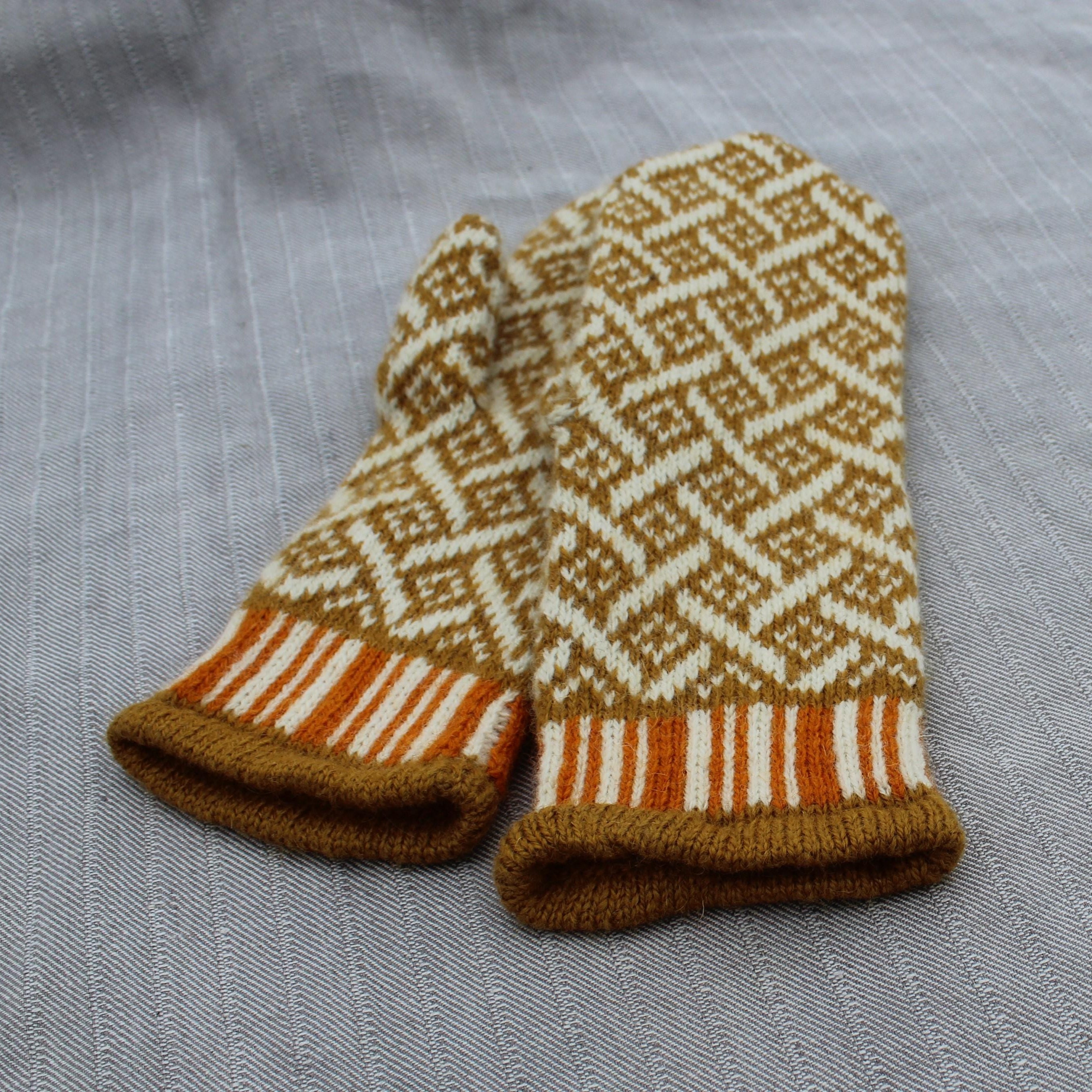 Pair of knitted mittens with a geometric pattern on a gray fabric background
