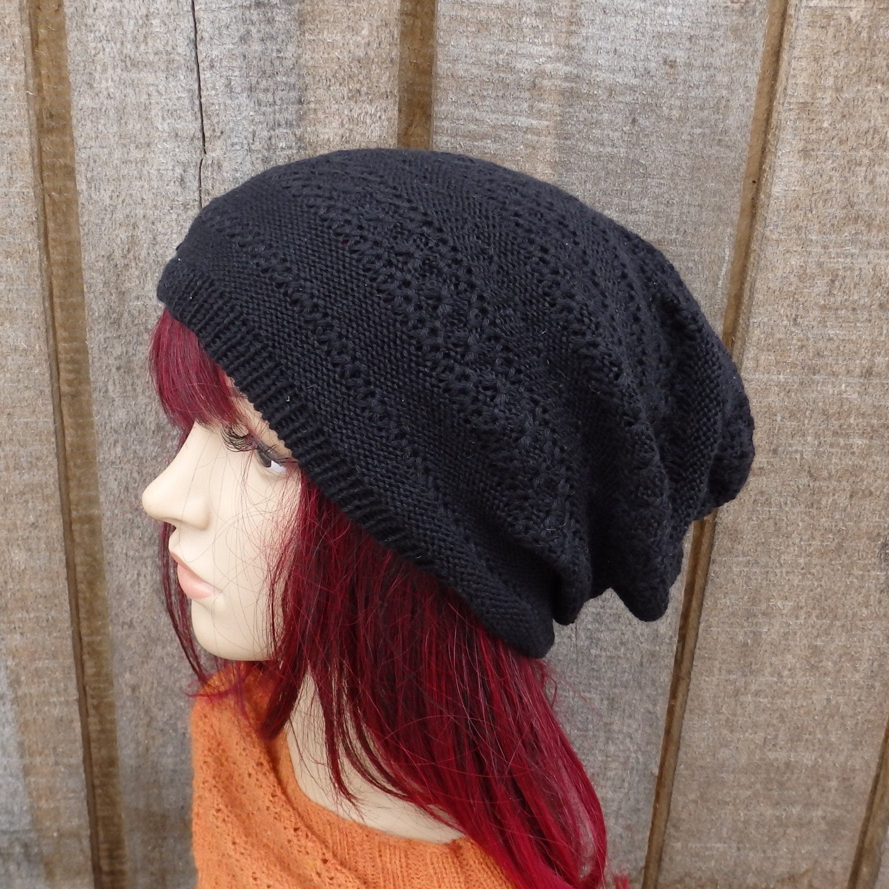 Person wearing a black knit beanie against a wooden panel background